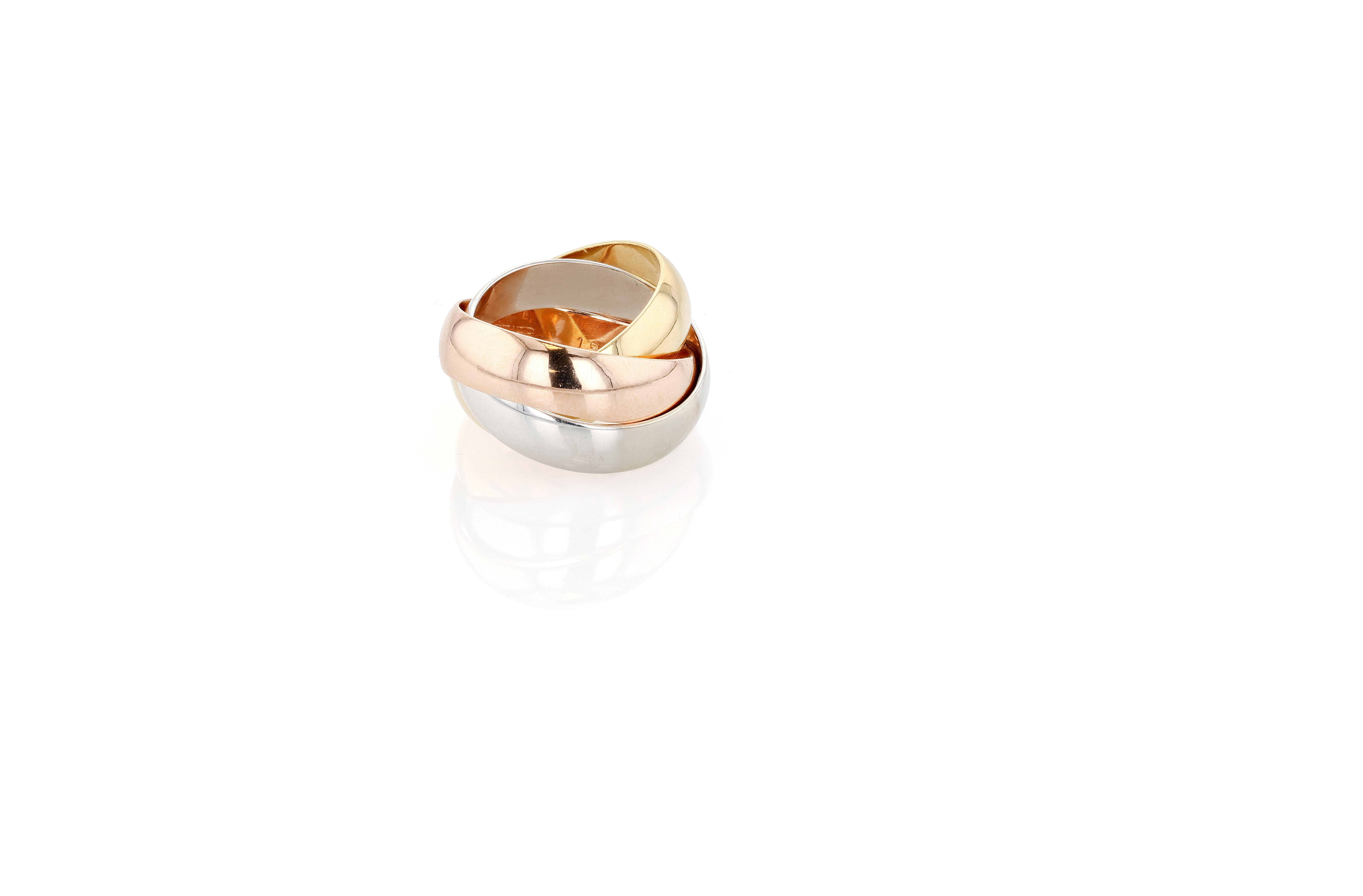 An 18 karat yellow, white, and rose gold Cartier Trinity rolling ring composed of three interlocking gold bands, each 5.2mm in thickness. 

Cartier Trinity was created in 1924, allegedly at the behest of Jean Cocteau who was obsessed with the rings