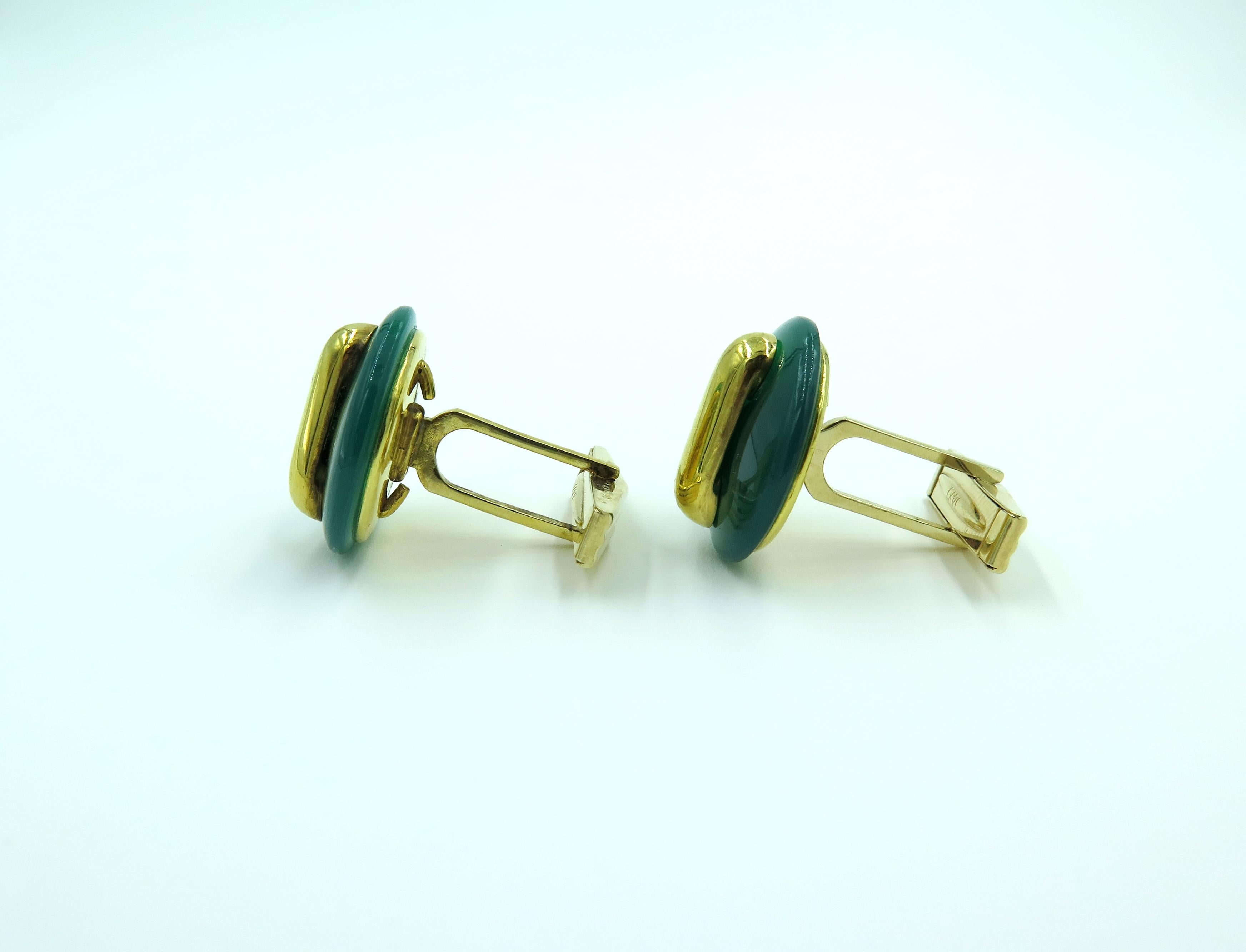 A pair of 18 karat yellow gold and green onyx cufflinks. Cartier. Circa 1970. Each single link set with a freen onyx dix, enhanced by a gold bar, with 14 karat yellow gold swivel back. Diameter is approximately 3/4 inch, gross weight is