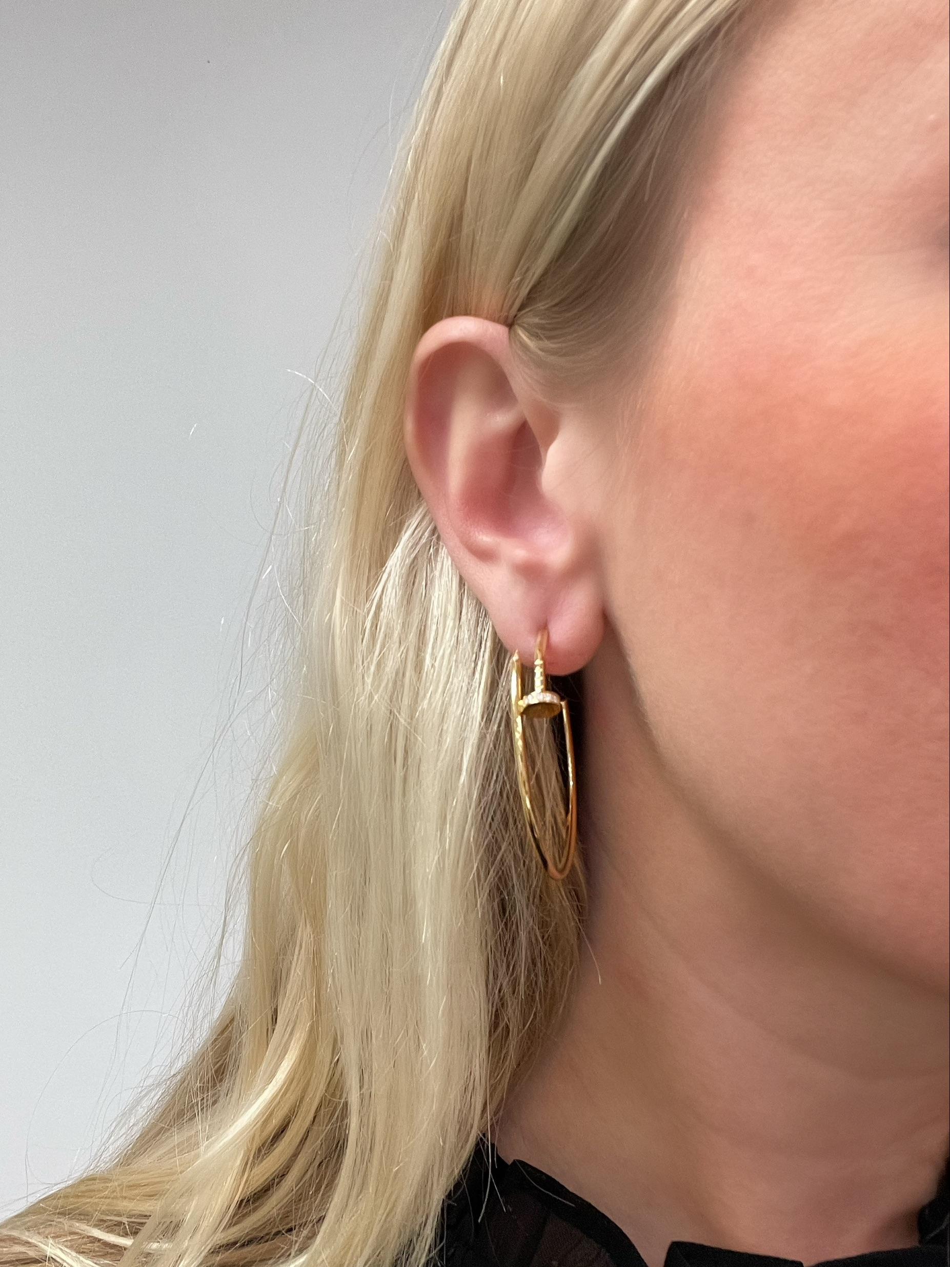 In a sleek modern nail design, these Cartier hoops from the Juste Un Clou collection, contain 28 round brilliant cut diamonds weighing 0.17 carat total.

Measurements: 1 3/4 inches long.
Metal: 18K yellow gold
Size: Large Model
Stamp: Cartier