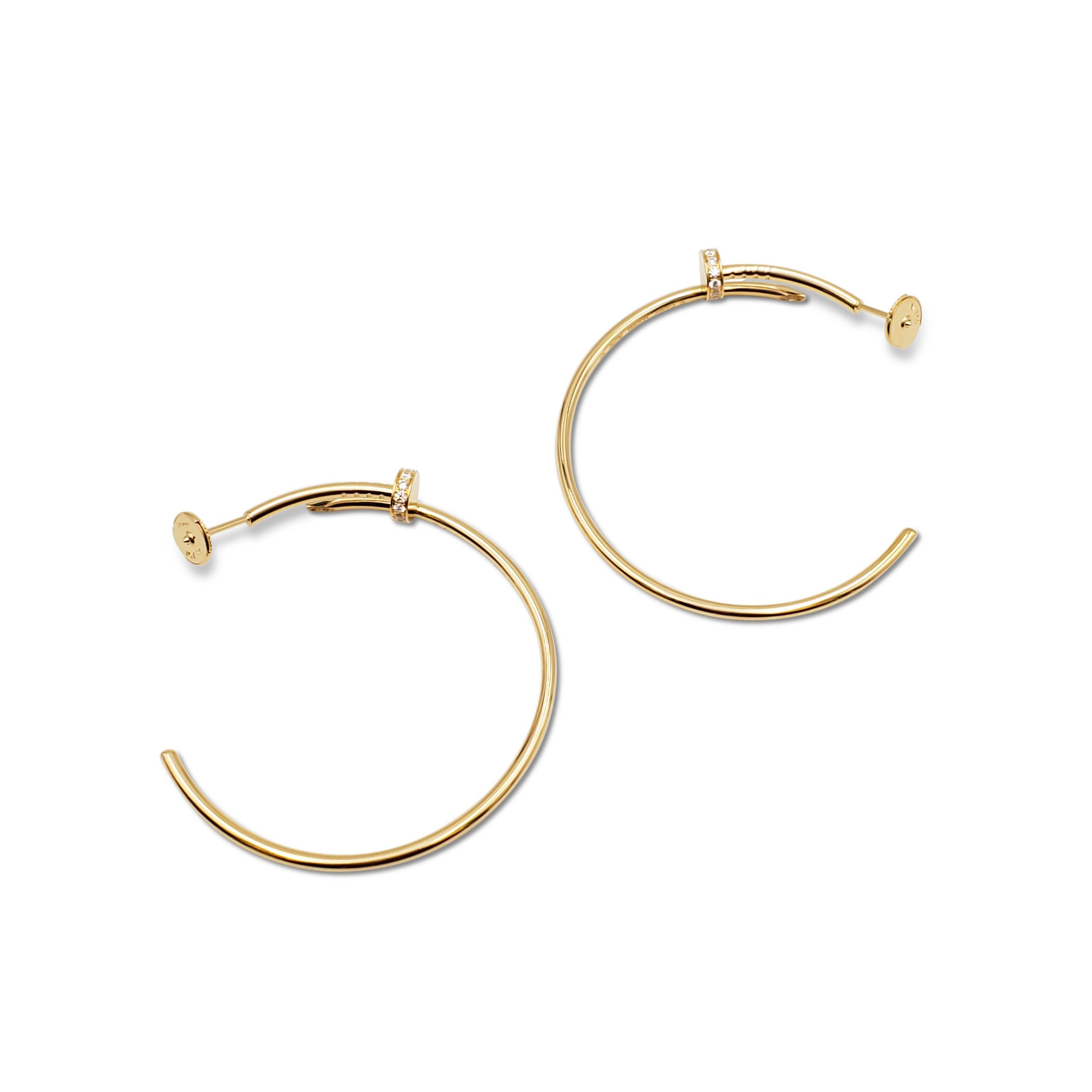 Authentic Cartier Juste Un Clou earrings crafted in 18 karat yellow gold features the iconic Cartier nail motif taking the shape of hoop earrings. The earrings are set with 28 round brilliant cut diamonds for an estimated 0.17 total carat weight.