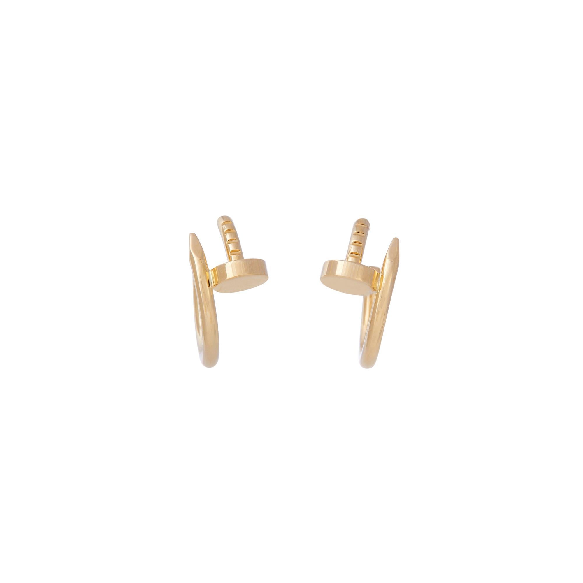 Authentic Cartier Juste un Clou earrings crafted in 18 karat yellow gold features the iconic Cartier nail motif taking the shape of small hoops.  The earrings measure .64 inches in length and 1.8mm wide.  Signed Cartier, Au750, with serial number