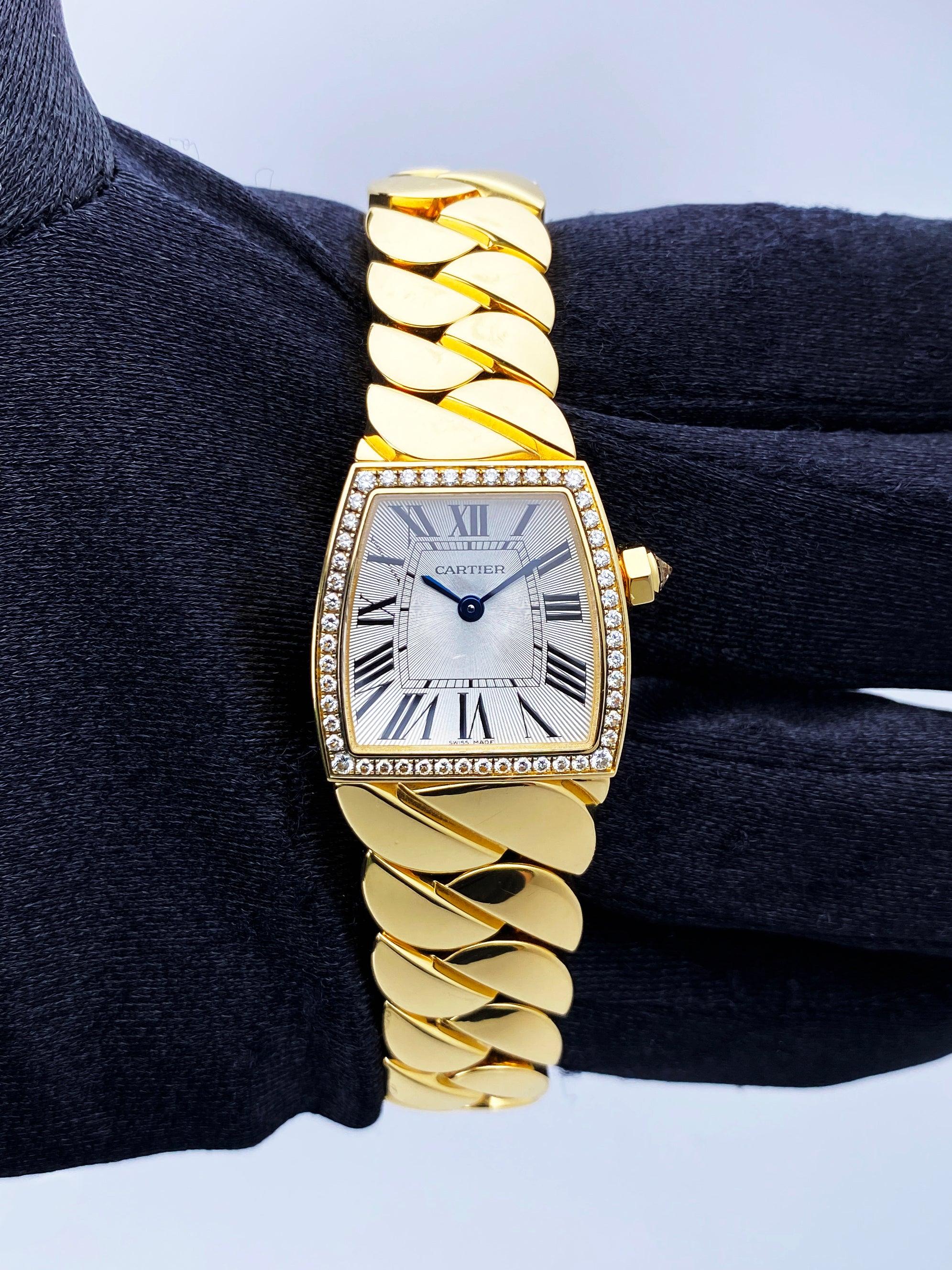 Cartier La Dona WE60040H Ladies Watch. 22mm 18K Yellow gold case with factory diamond set. Silver dial with blue hands and black Roman numeral hour marker. Minute markers on the inner dial. 18K yellow gold bracelet with a hidden butterfly clasp.
