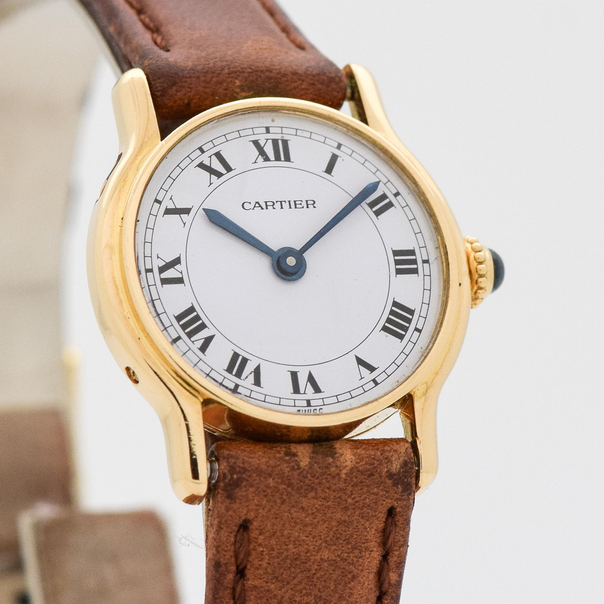 2000's Cartier Ladies Round-shaped 18k Yellow Gold watch with Original White Dial with Black Roman Numerals. Rare. 23mm x 27mm lug to lug (0.91 in. x 1.06 in.) - 17 jewel, manual caliber ETA movement. Genuine Leather Brown-colored Watch Strap. 