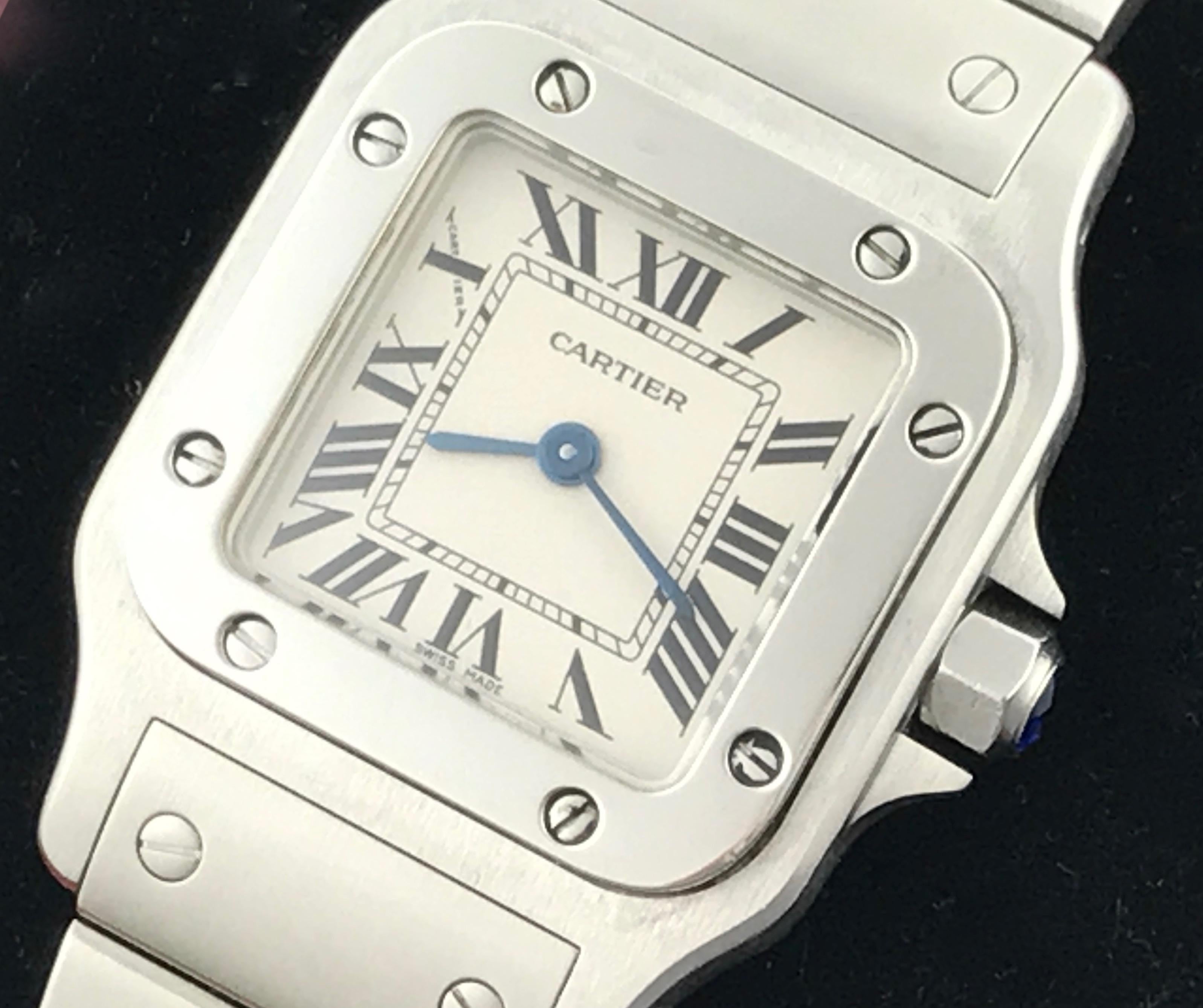 Cartier Ladies Santos Model W20056D6 Stainless Steel Wrist Watch.  Quartz movement.  Stainless Steel square style case with blue sapphire cabachon setting crown (24x34mm). Water Resistant to 30 Meters - 100 Feet. Stainless Steel bracelet with