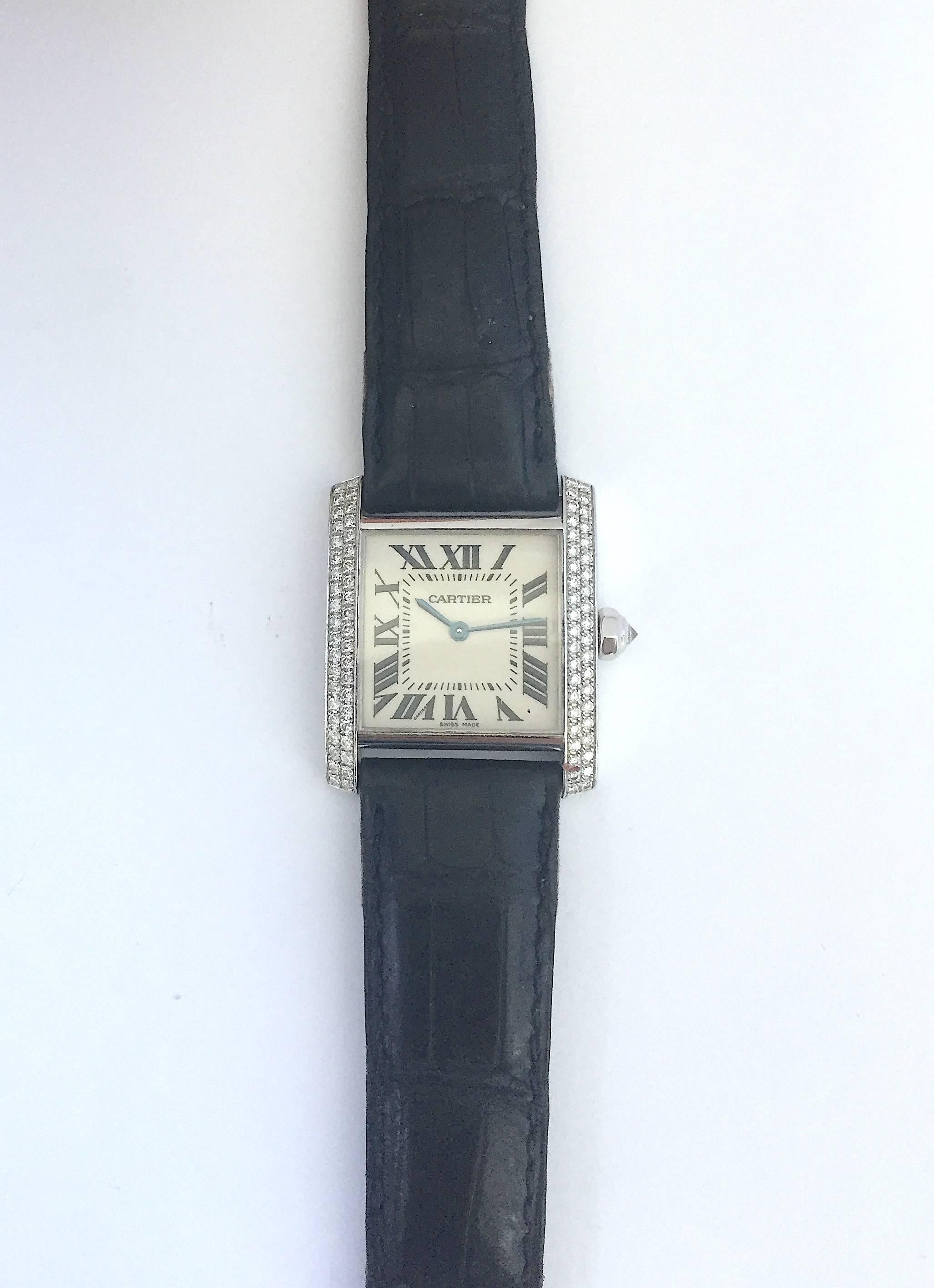 Cartier 18K White Gold Ladies Tank Quartz Watch
Classic Cartier Tank Design with Roman Numeral Markers 
White Colored Dial with Cartier Blue Hands 
Cartier Cabochon Diamond Crown 
Sapphire Crystal 
Quartz Movement 
Factory Diamond Bezel
Comes Fitted