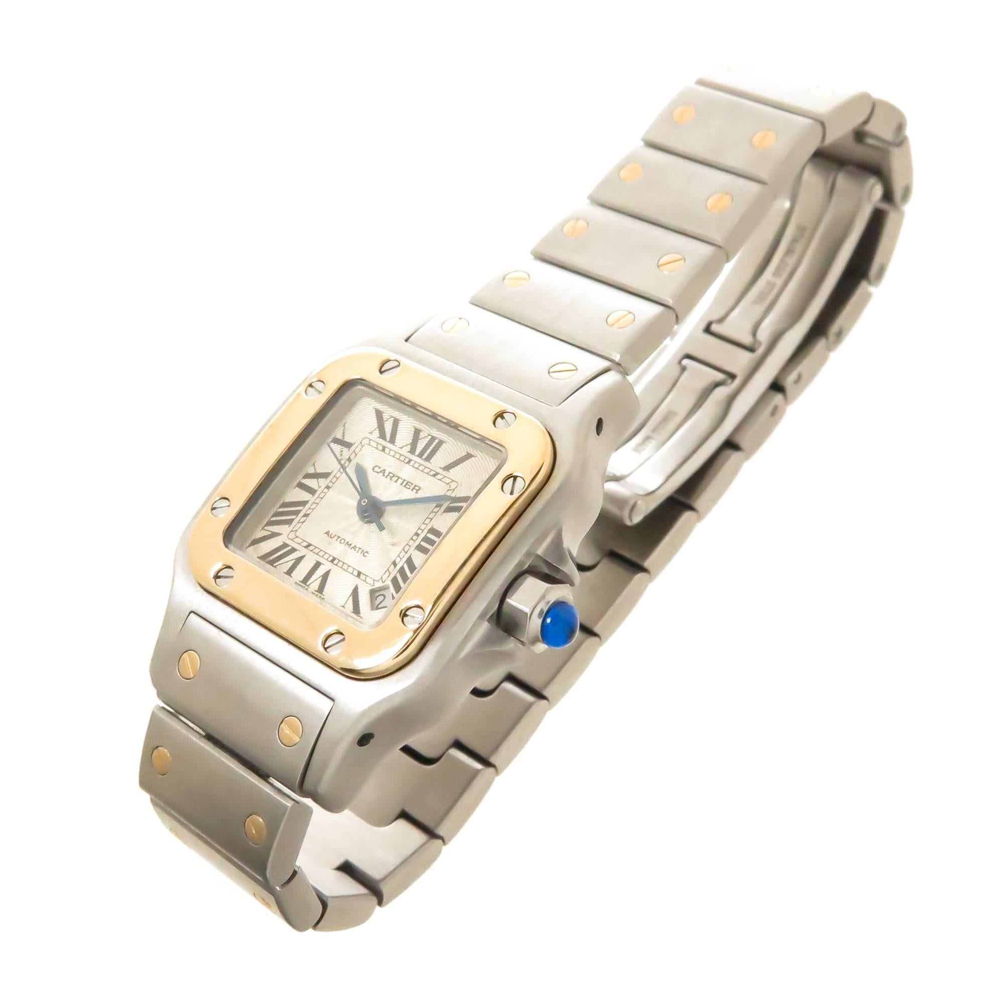 Circa 2000 Cartier Santos Ladies Wrist Watch, 34 X 24 MM Stainless Steel case with 18K yellow Gold Bezel. Automatic, Self Winding Movement, Silver Engine Turned Dial with Black Roman Numerals a Calendar window at the 5 position and a sapphire crown.