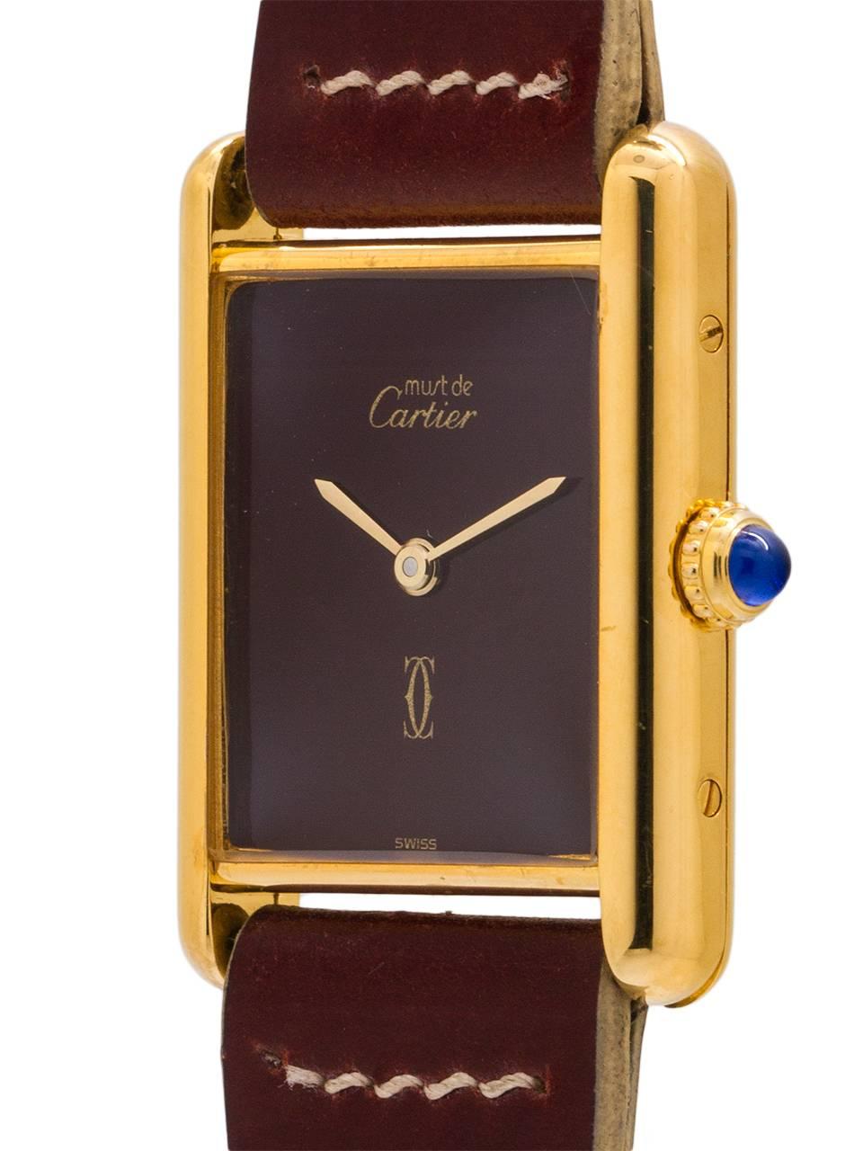 
Cartier lady’s vermeil Tank Louis circa 1980s. Featuring a 21 X 27mm case secured by 4 side and 4 caseback screws. Featuring original burgundy color dial signed Must de Cartier and with Cartier double C logo, gilt hands, and blue cabochon sapphire