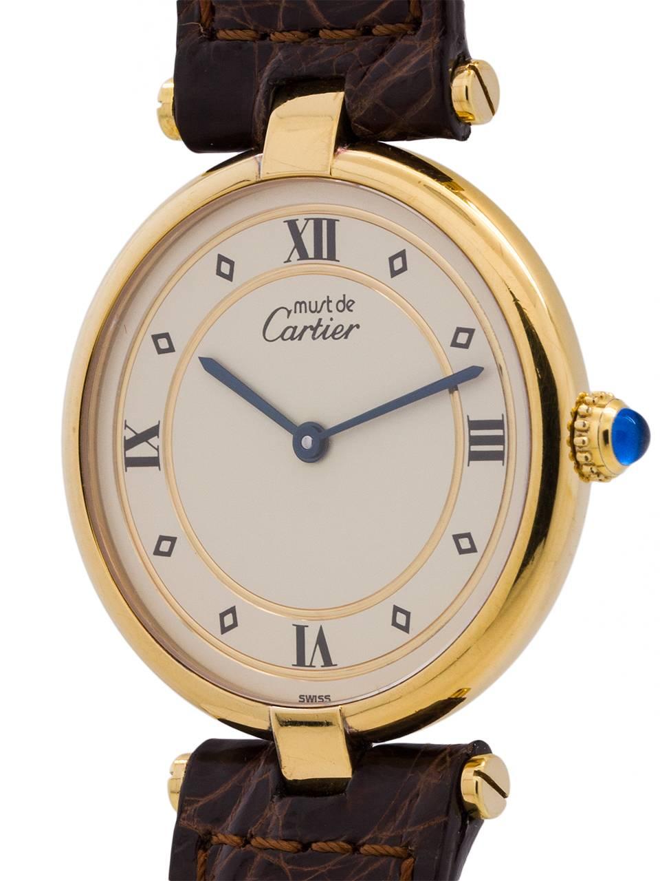 Cartier Man’s vermeil Vendome Tank Must de Cartier circa 1990s. Featuring a 30.5 x 37mm round case with “T bar” lugs and sapphire crystal. Classic cream dial with black roman numerals, blue steeled hands, and blue cabachon sapphire crown. Battery