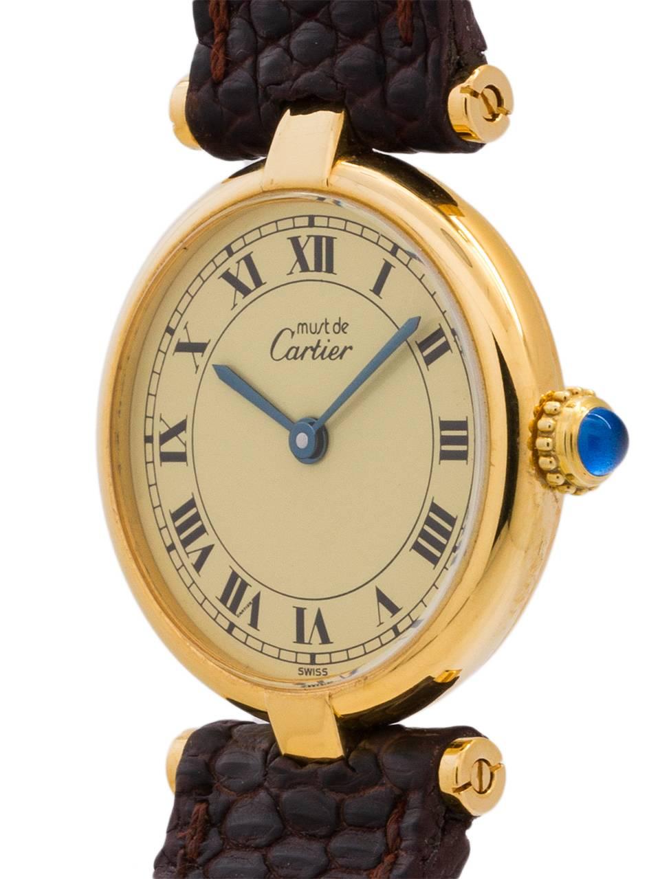 
Cartier Lady’s vermeil Vendome Tank Must de Cartier circa 1990s. Featuring a 24.5 x 30mm round case with “T bar” lugs and sapphire crystal. Classic cream dial with black roman numerals, blue steeled hands, and blue cabachon sapphire crown. Battery