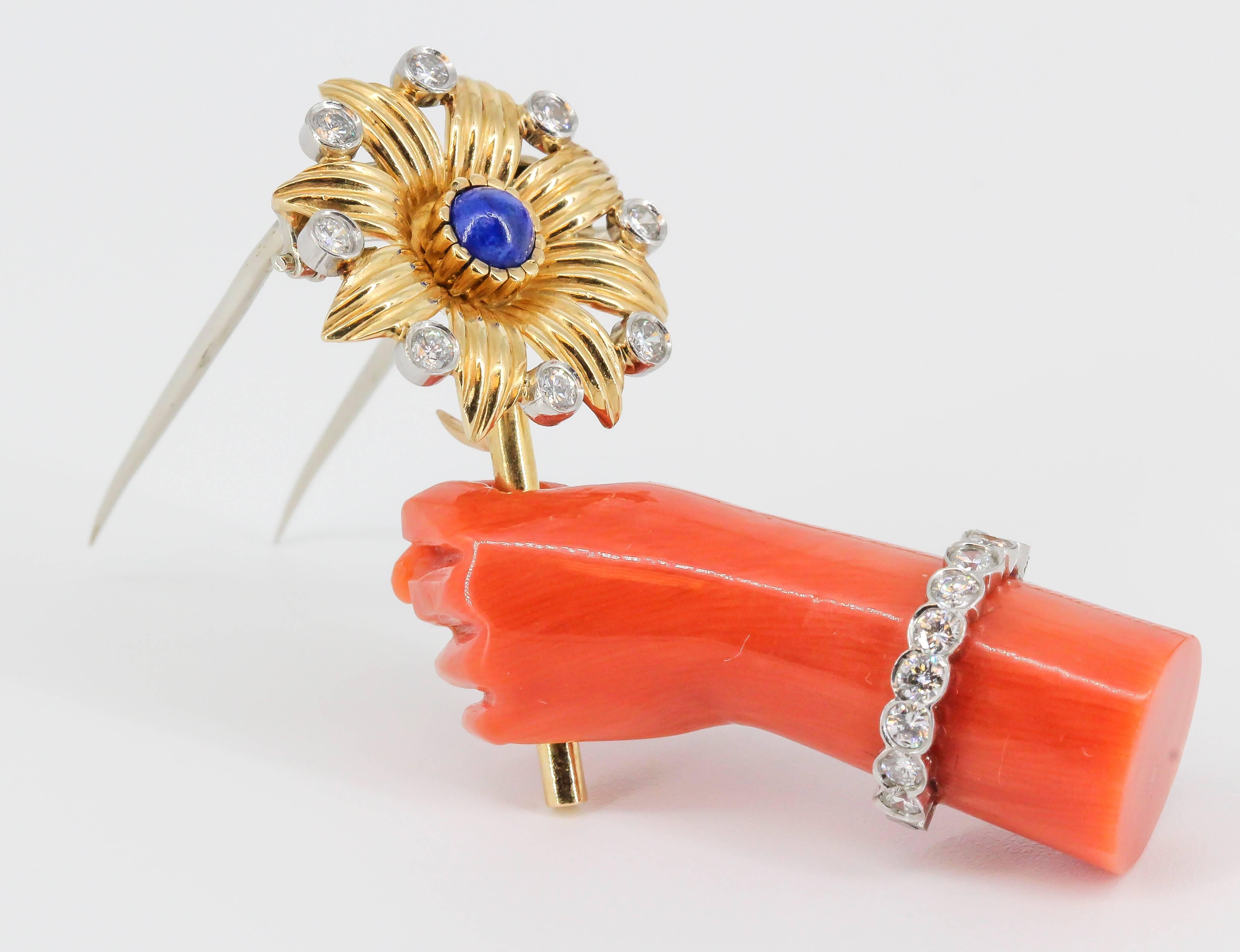 Rare lapis, diamond, platinum, coral and 18K yellow gold brooch by Cartier, of French origin circa 1960s. It resembles a hand holding a flower. The hand is made of rich coral, with high grade round brilliant cut diamonds around it as a bracelet; the
