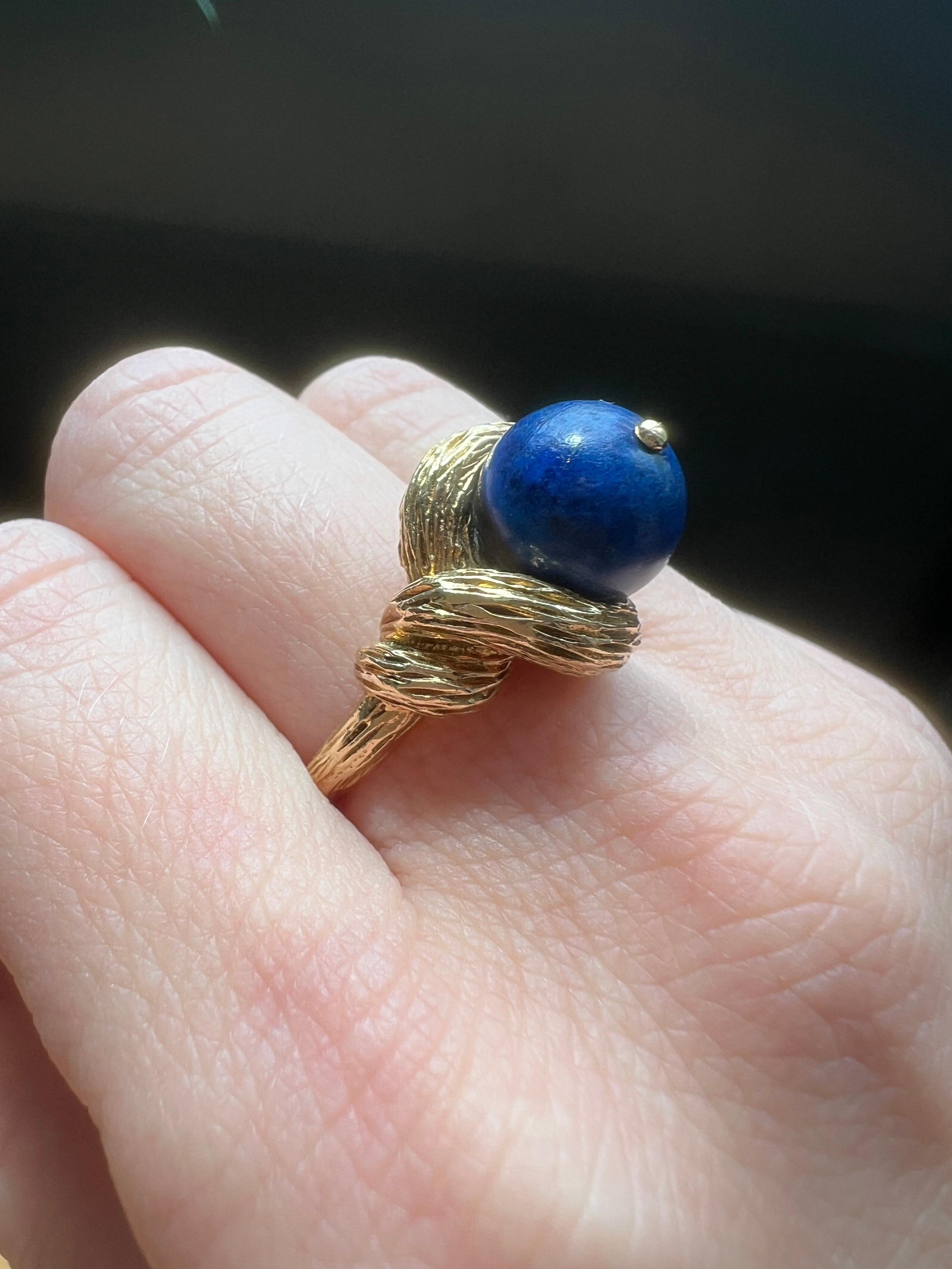 Un sorprendente anello Cartier vintage in oro giallo 18 carati, con un grande lapislazzuli cabochon incastonato in un vortice scultoreo d'oro fortemente strutturato. La forma organica e la composizione audace riflettono l'estetica distintiva degli