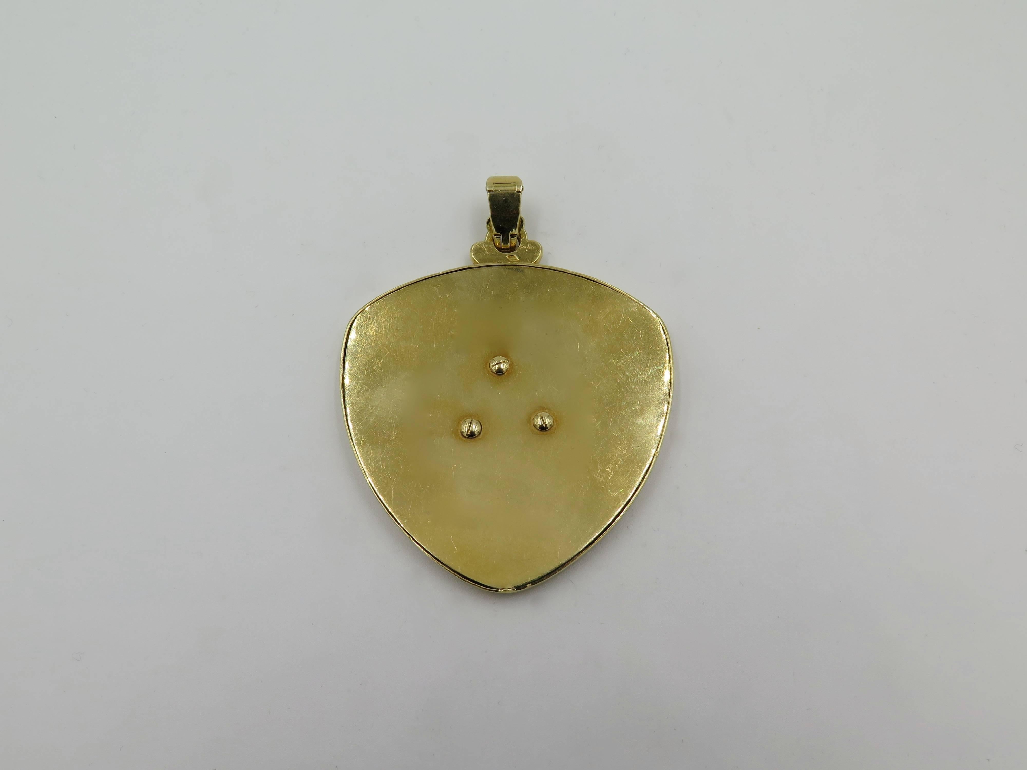 An 18 karat yellow gold, lapis lazuli and mother of pearl pendant.  Cartier Paris. Circa 1970. Of shield shaped outline, set with inlay mother of pearl, enhanced by applies lapis lazuli floral motifs. Length is approximately 3 inches (including