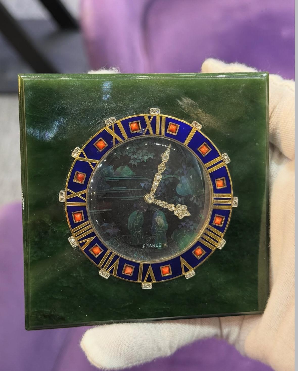Cartier Laque Art Deco Burgaute Lack Tischuhr

Viereckige Cartier-Uhr mit Jade-Gehäuse und Burgaute-Lack-Perlmutteinlage, die zwei Frauen in einem Garten darstellt. Die Vorderseite ist mit blauer Emaille und römischen Ziffern verziert, die von