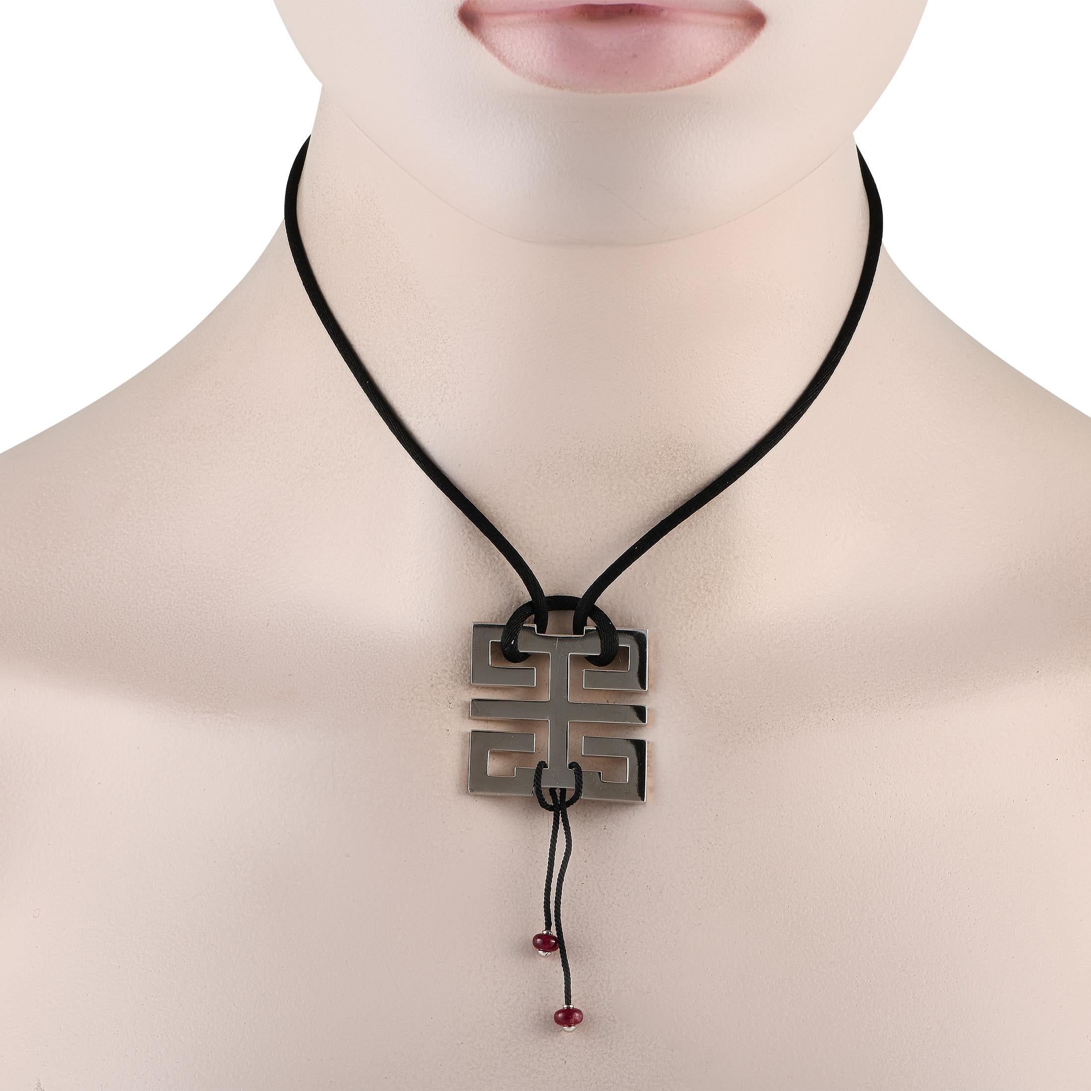 This Cartier Le Baiser du Dragon exudes obvious Eastern influence. Suspended from a 24 black silk cord, youll find a bold 18K White Gold pendant measuring 1.25 long by 1.25 wide. Red gemstones hanging below provide a touch of extra color.This