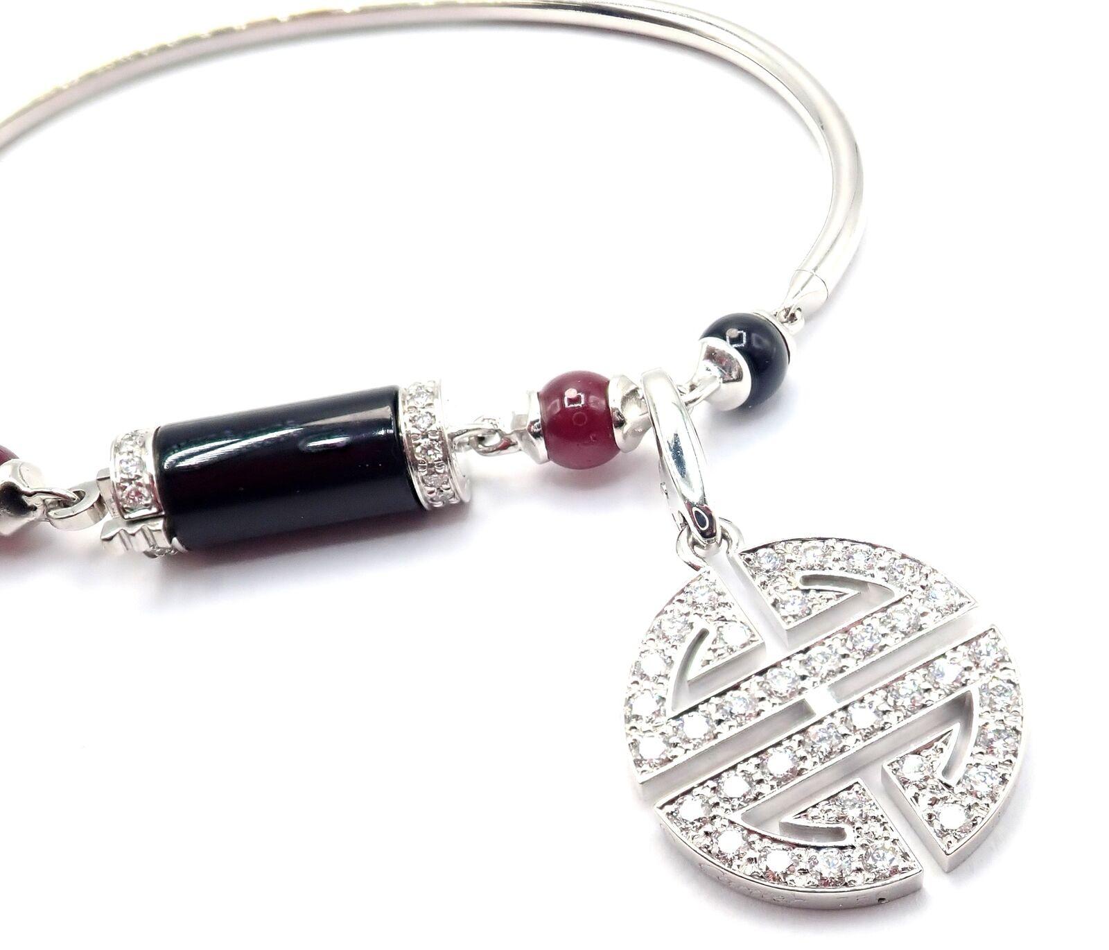 18k White Gold Ruby Onyx Bangle Le Baiser Du Dragon Bracelet With Two Charms by Cartier. 
Part of the Cartier Le Baiser Du Dragon Collection. 
With Round brilliant diamonds, E color, VVS1 clarity total weigh approximately 1.50ct
3 rubies
3 black