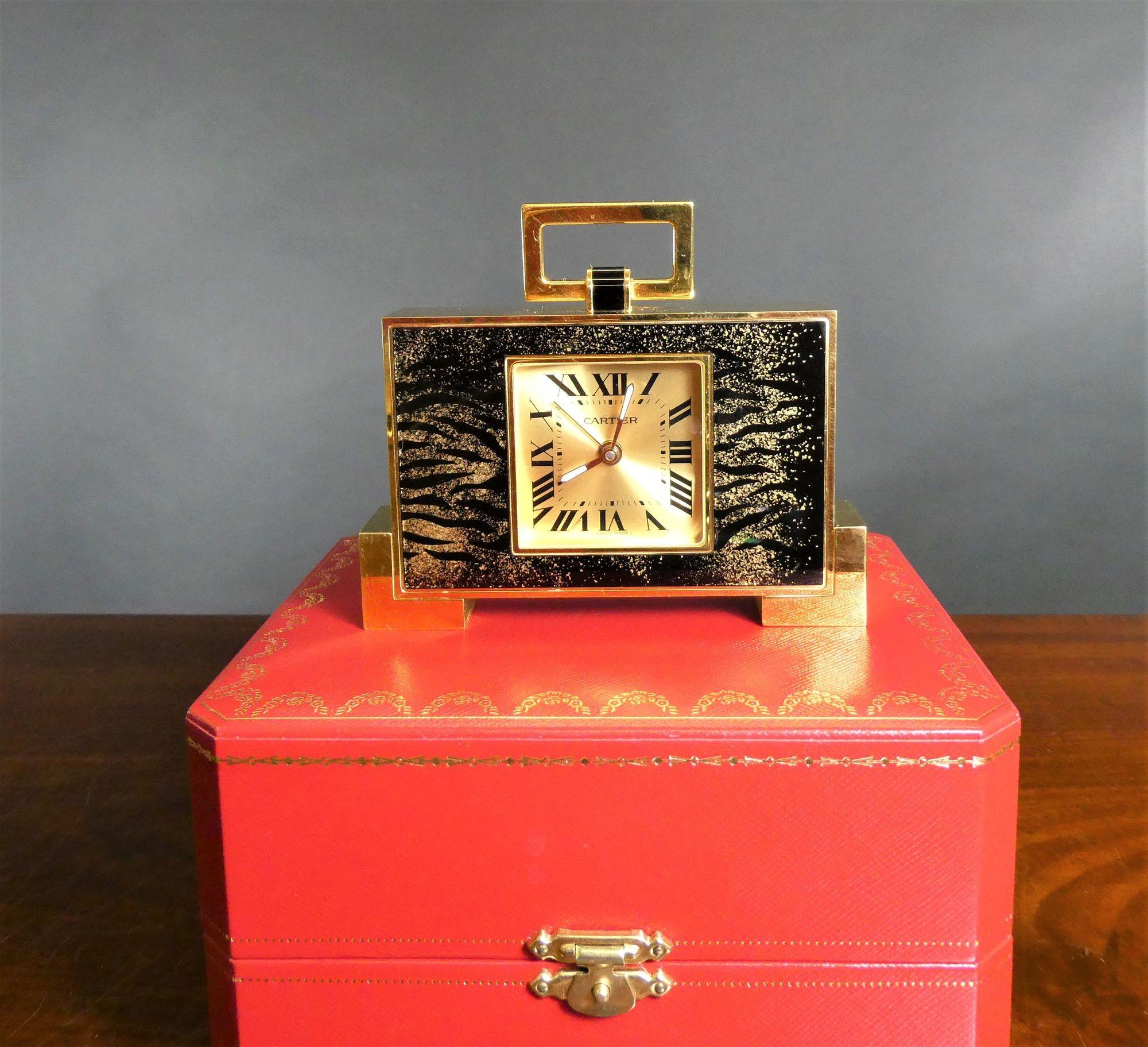 Cartier ‘Leopard Print’ travel alarm clock.
 
 
Cartier ‘Leopard Print’ travel alarm clock housed in a rectangular case with hinged carrying handle.
Square dial with Roman numerals, original hands and signed ‘Cartier’.
Quartz movement with