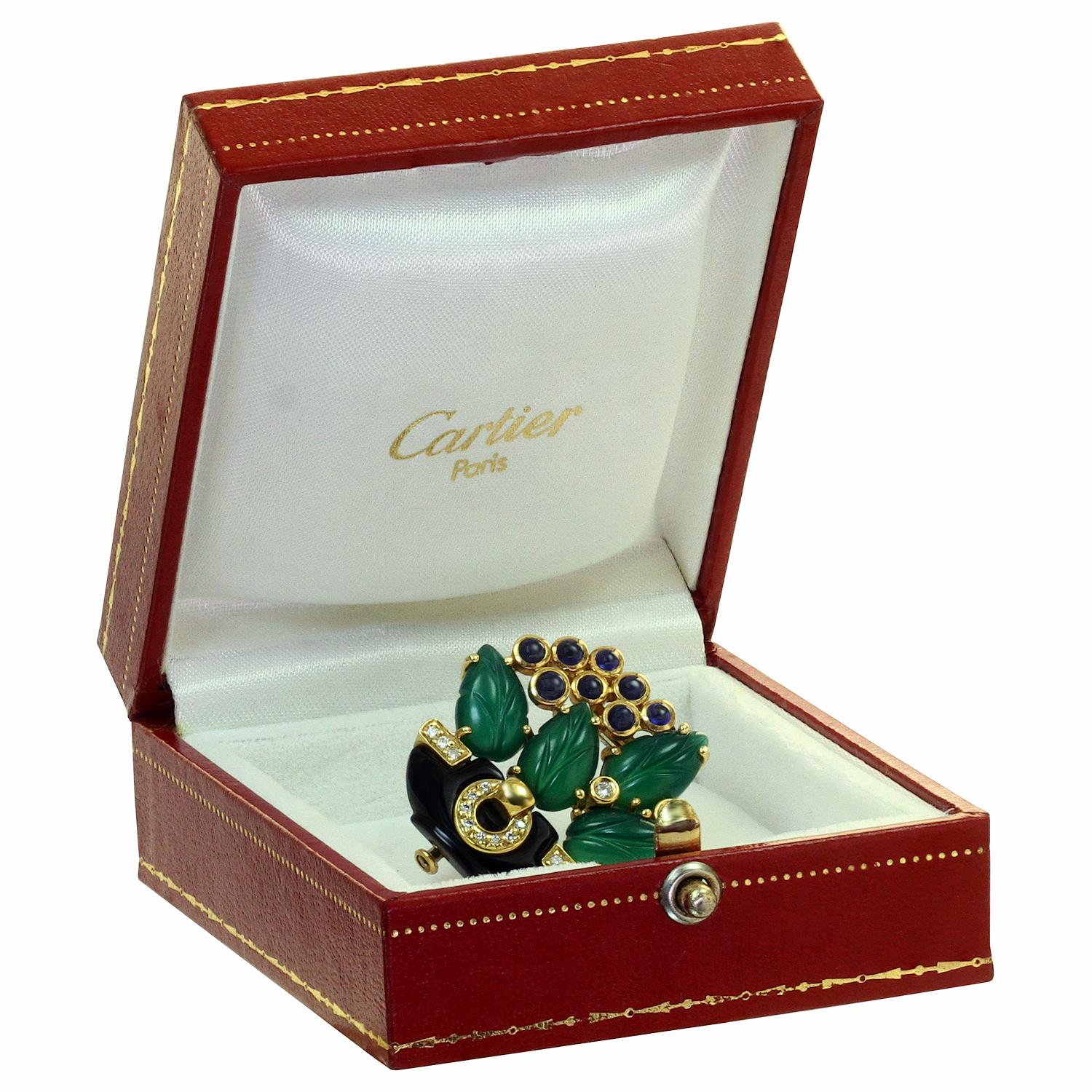 This exquisite brooch from Cartier's celebratede Les Indes Galantes collection features a floral design composed of a black onyx bowl accented with full-cut paved diamonds, green curved agate leaves, round cabochon blue sapphires and brillant-cut