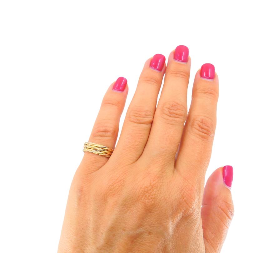 Un elegante e intramontabile anello a trinità Les Must de Cartier, realizzato in oro giallo, bianco e rosa 18 ct. L'iconico design è caratterizzato da tre fasce intrecciate che simboleggiano unità e raffinatezza. Ciascuna fascia in corda