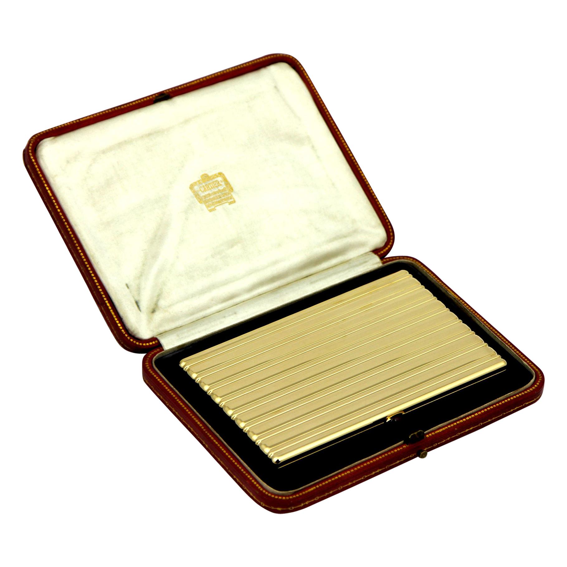 A rectangular 18 karat yellow gold cigarette case, by Cartier, dated 1947, with fitted presentation box. The exterior surface of the case is patterned with undulating horizontal stripes. The push-in ruby cabochon thumb-piece opens the case to reveal
