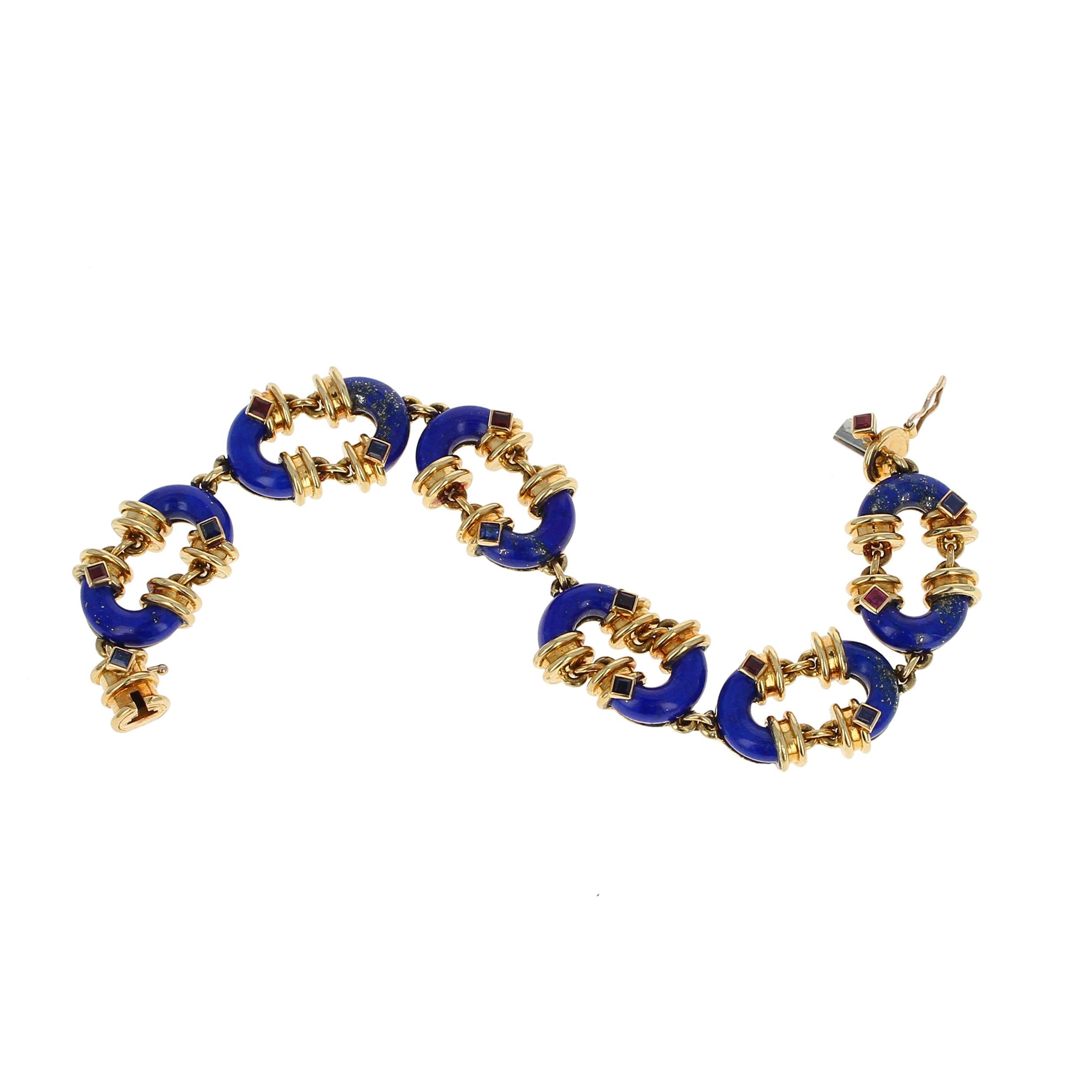 A remarkable and chic Lapis Lazuli bracelet by Cartier. This link bracelet, designed with Cartier's symbolic 'C', is entirely crafted with 18kt yellow gold and set with alternating square-cut rubies and sapphires. The bracelet is stamped Cartier