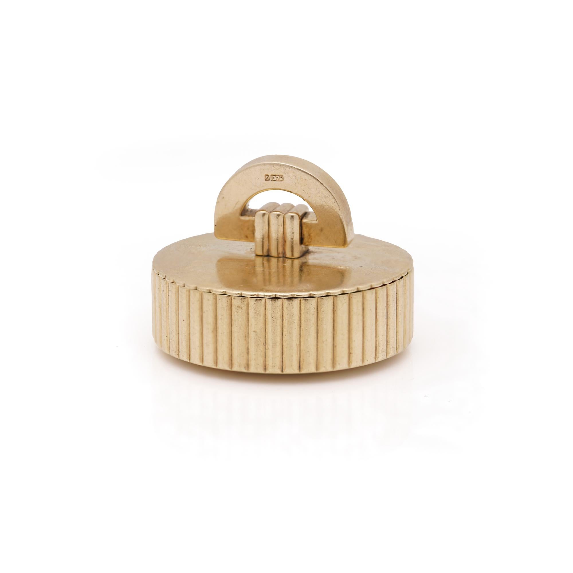  Cartier London retro round 9kt yellow gold pillbox.

The interior of the pillbox is marked with Cartier London hallmarks. 
The bottom is simple and flat, featuring a prominent closure mechanism, which looks like a screw-shaped clip. 
The sides of