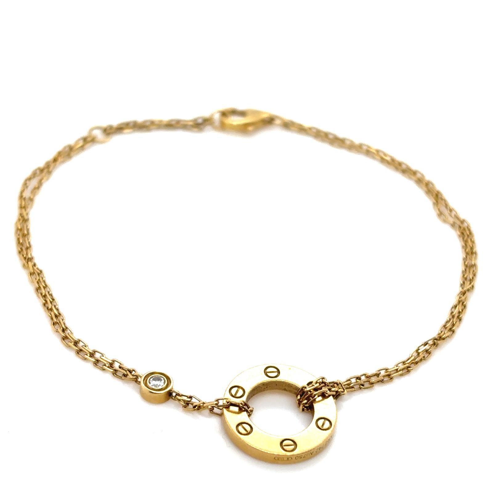 A Cartier Love 18 karat yellow gold two diamond set bracelet

Designed as a double row cable link chain bracelet, featuring Cartier's iconic Love heart circular gold disc to one end, and two bezel set round brilliant cut diamonds of 0.04 carats in