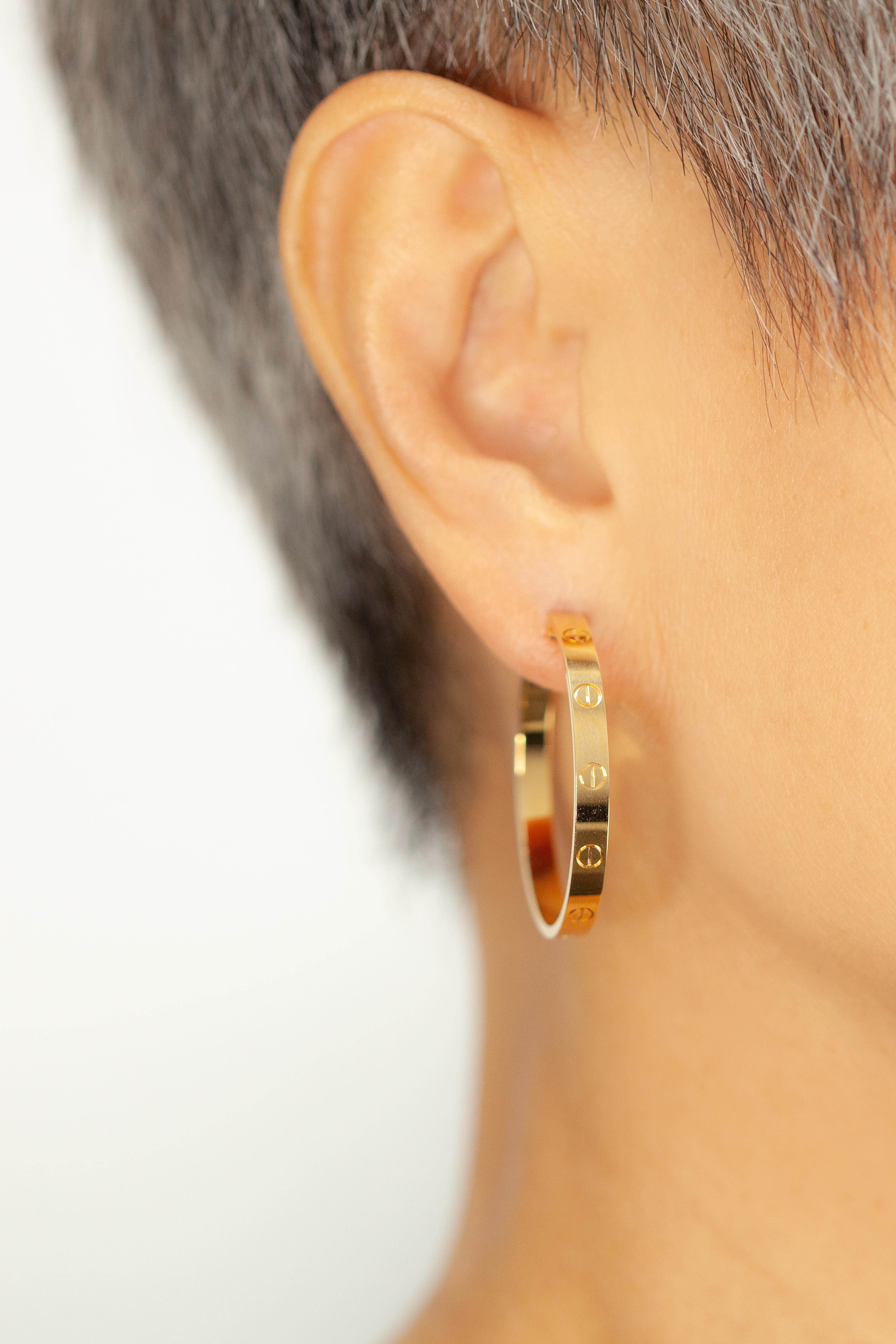 Une paire classique de grandes boucles d'oreilles Cartier Love, finement travaillées en or 18 carats. Le motif iconique de la vis, synonyme de la collection intemporelle Love de Cartier, entoure les anneaux avec une élégance moderne.

Prix de détail