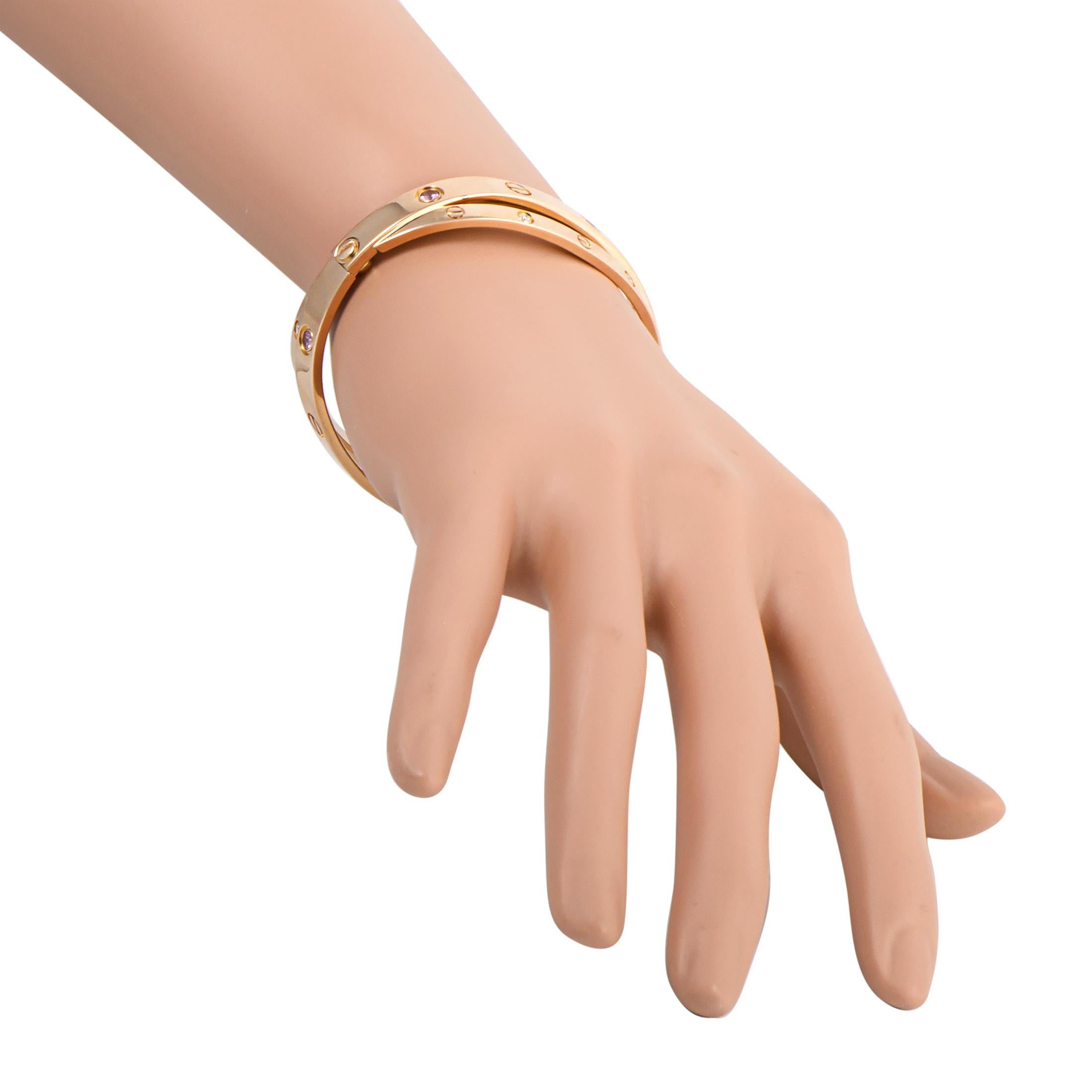 This vintage “LOVE” bracelet by Cartier is made of 18K rose gold and embellished with diamonds and pink sapphires. The bracelet weighs 47.4 grams and boasts a 2.50” diameter. This item is delivered with a screwdriver.
This  bracelet includes the
