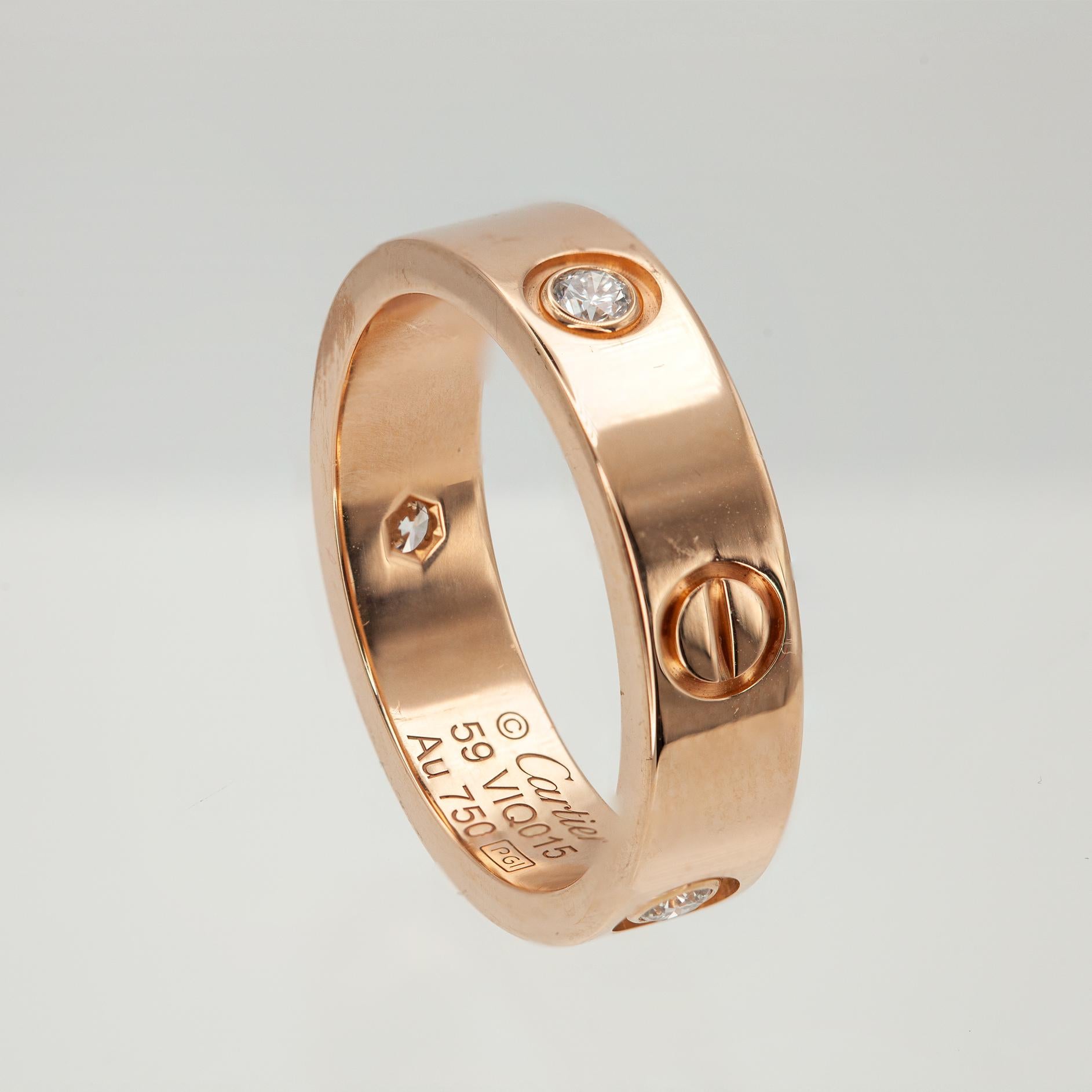 Un clásico intemporal de Cartier, este auténtico anillo LOVE de Cartier está maravillosamente elaborado en oro rosa de 18 quilates y engastado con tres diamantes redondos talla brillante. Diseñado con el característico motivo de tornillo de la