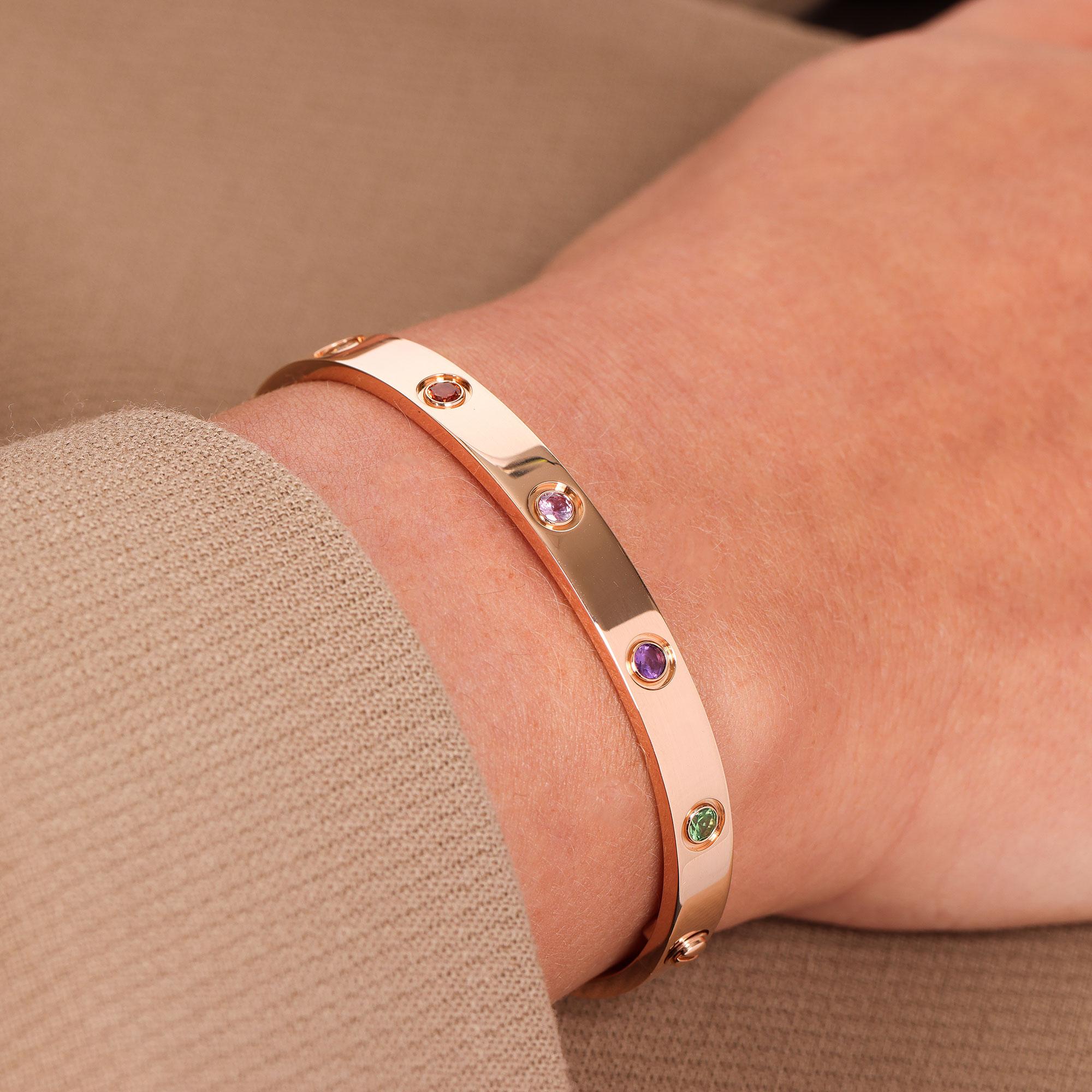 This bracelet by Cartier is from their Love collection and features a combination of gemstones. There are 2 pink sapphires, 2 yellow sapphires, 2 green garnets, 2 orange garnets and 2 amethysts all set in 18ct rose gold. It is a Cartier size 17 and