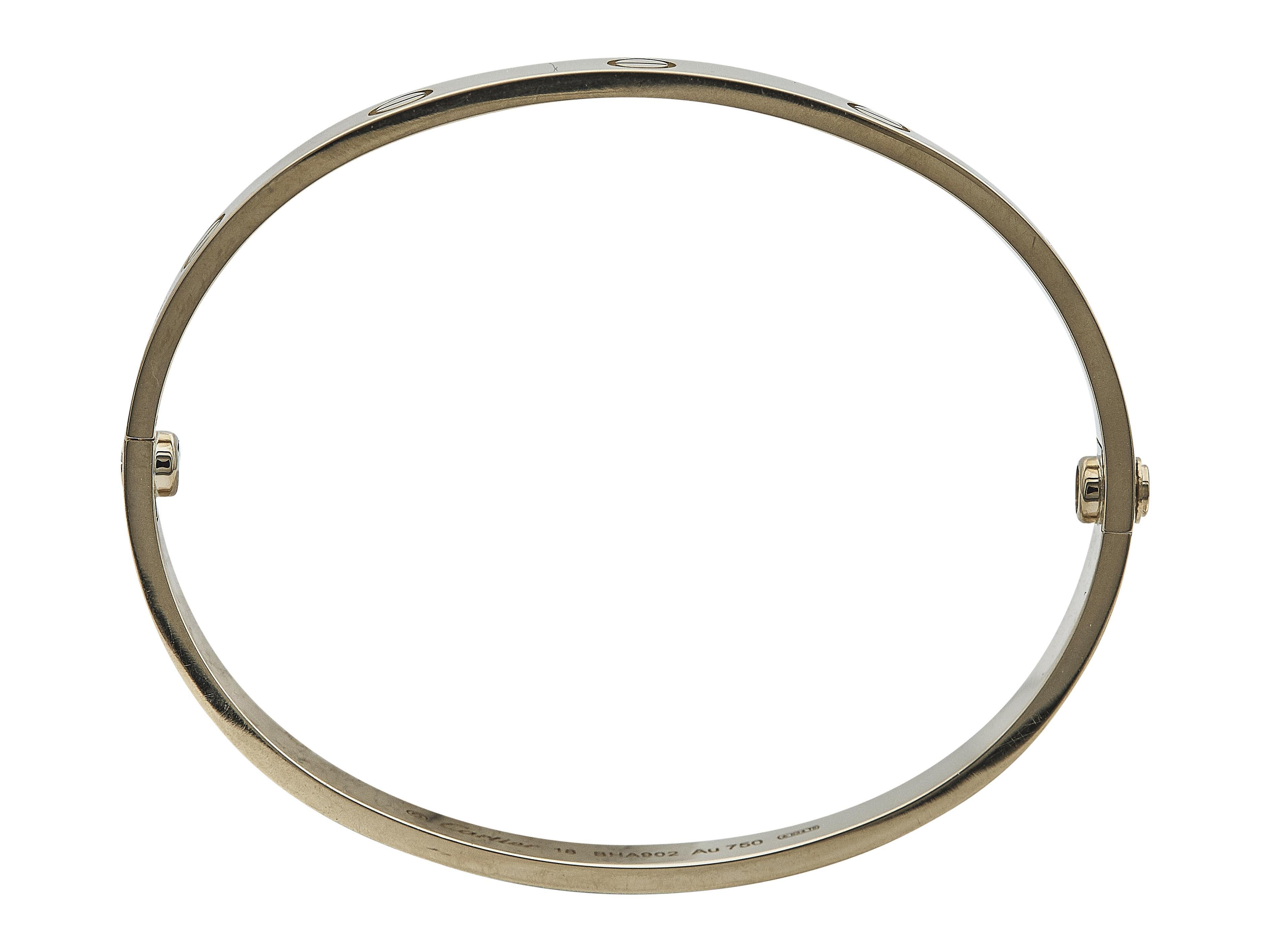 La pulsera:
Una pulsera brazalete Cartier Love. Este modelo Clásico está fabricado en oro de dieciocho quilates y presenta el icónico diseño con motivo de tornillo. Es una talla 18.

La pulsera está en excelente estado, con mínimos signos de