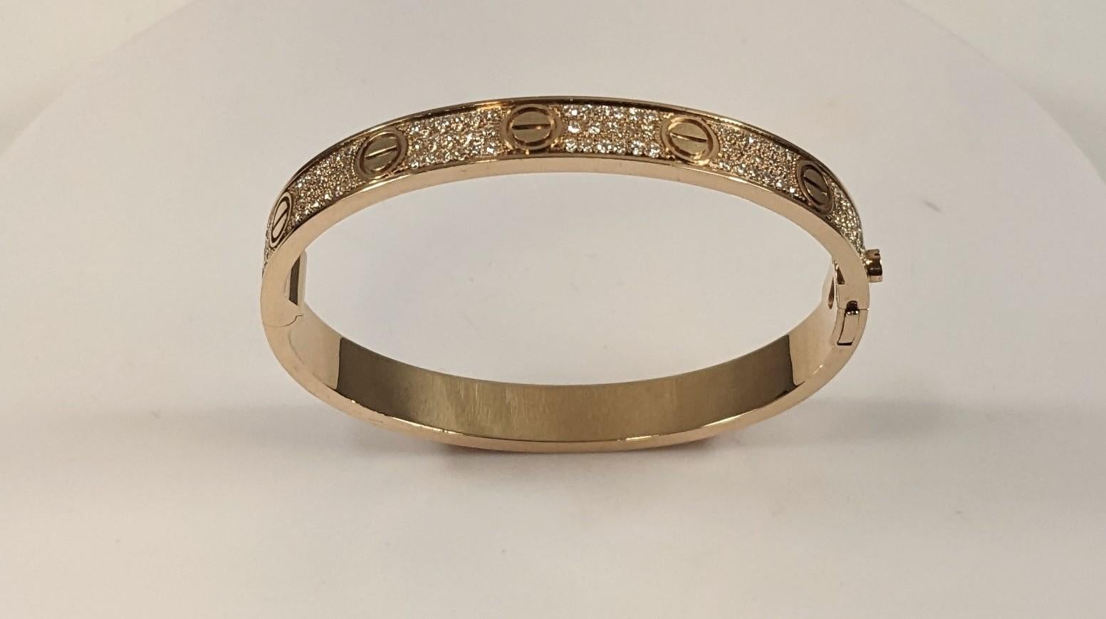 CARTIER LOVE BRACELET
Cartier 'Love' bangle bracelet crafted in 18k rose gold with gold screw tops and pave set round brilliant cut diamonds (D-F in color, VVS clarity)
Signed Cartier,  750, with serial number and hallmarks 
The bracelet is