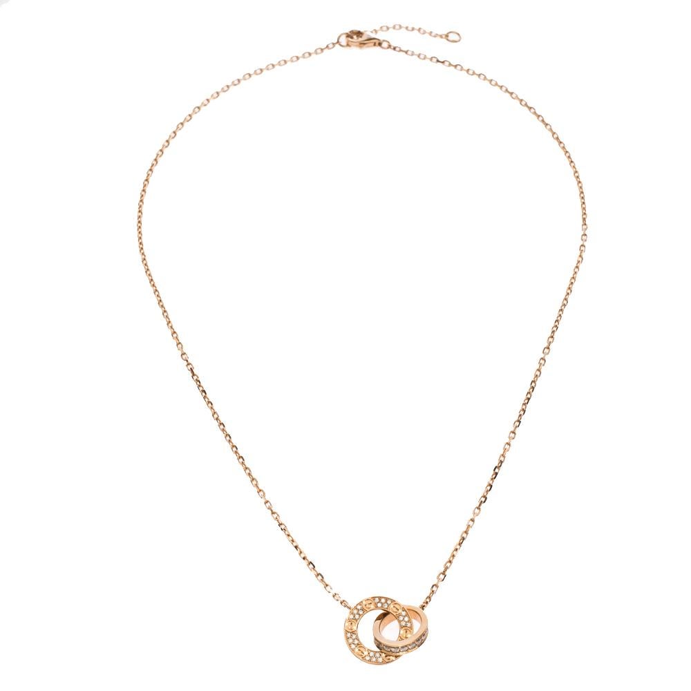 Celebrate timeless love with this necklace from Cartier's Love collection. It is made from 18K rose gold and the chain holds two interlocking rings pendant decorated with the iconic screw motifs and pavé diamonds of approximately 0.30ct. Each piece