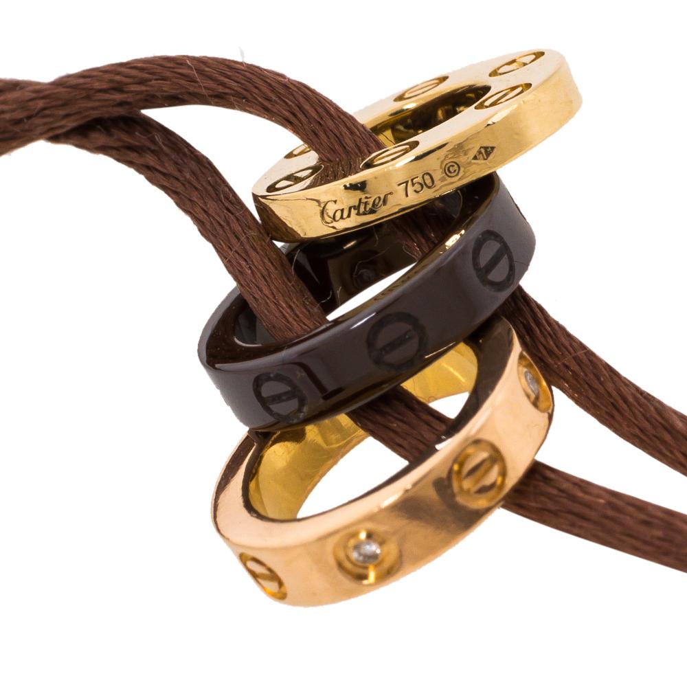 Dating back to the 70′s as a symbol of commitment, the LOVE collection by Cartier salutes everlasting love and passion. Display your love in style with this sleek silk cord bracelet holding signature Cartier rings in 18k gold and ceramic.

