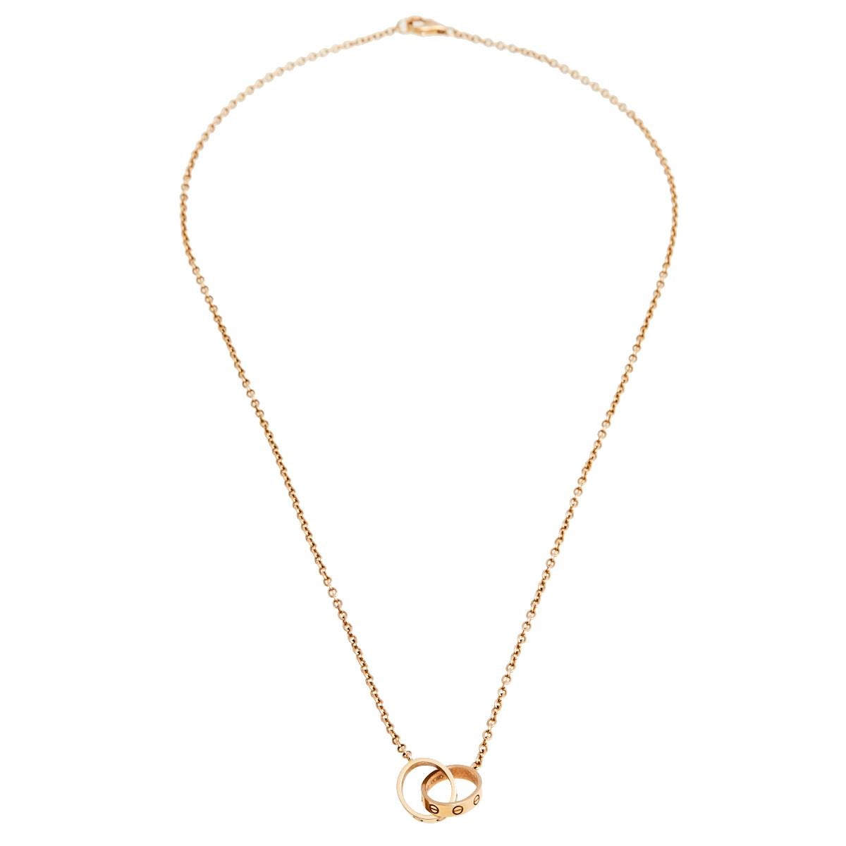 Celebrate timeless love with this necklace from Cartier's Love collection. It is made from 18k rose gold and the chain holds two magnificent hoops interlocked with one another. Both the rings carry the iconic screw motifs which are a signature of