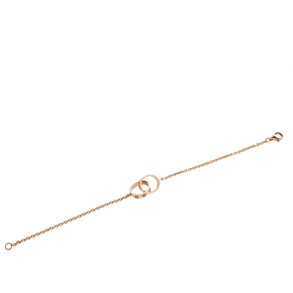 Celebrate timeless love with this bracelet from Cartier's LOVE collection. Made from 18k yellow gold, it has a chain that holds two magnificent rings interlocked with one another. On both, one can see the iconic screw motifs which are a signature of