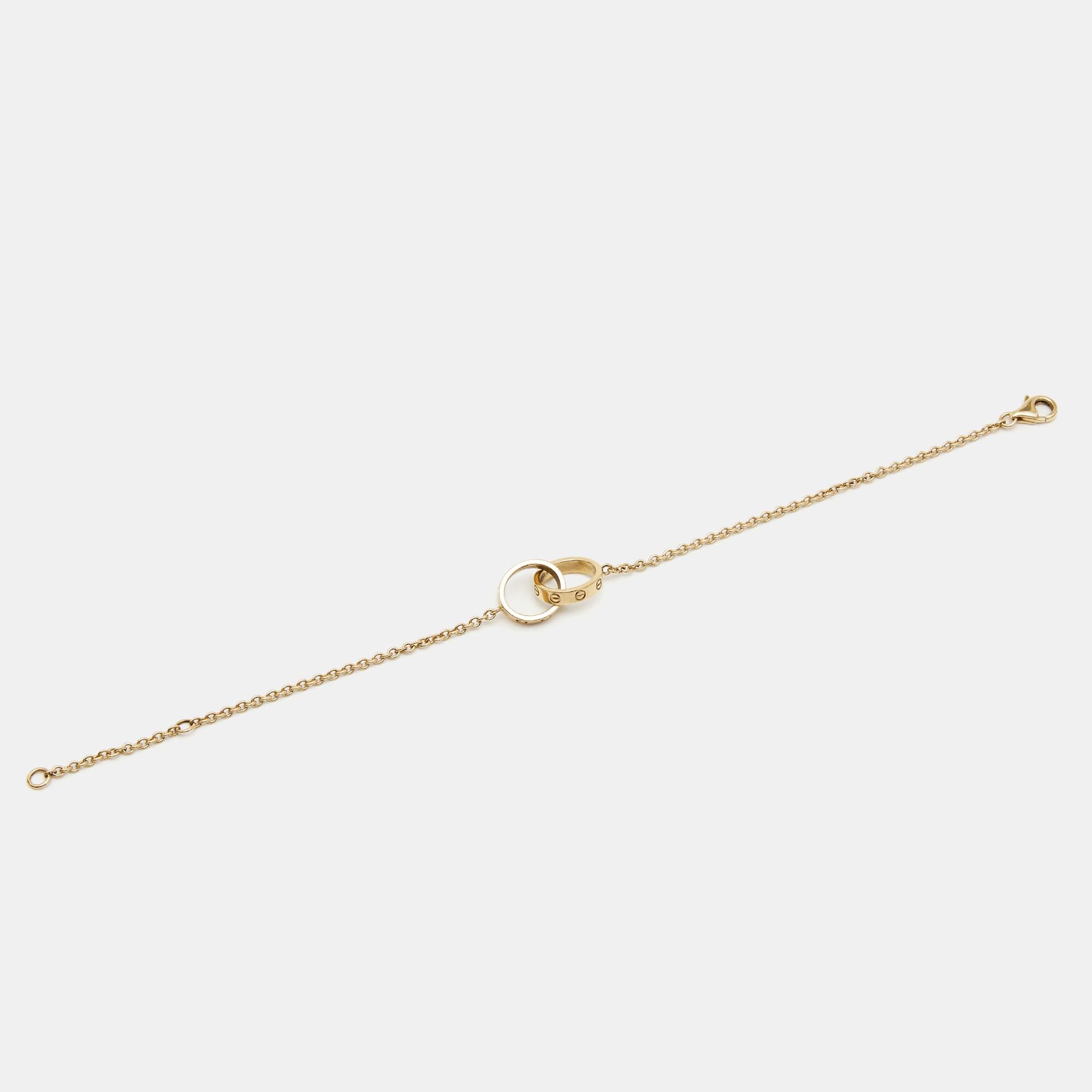 Celebrate timeless love with this bracelet from Cartier's Love collection. Made from 18k yellow gold, it has a chain that holds two magnificent rings interlocked with one another. On both, one can see the iconic screw motifs — a signature of the