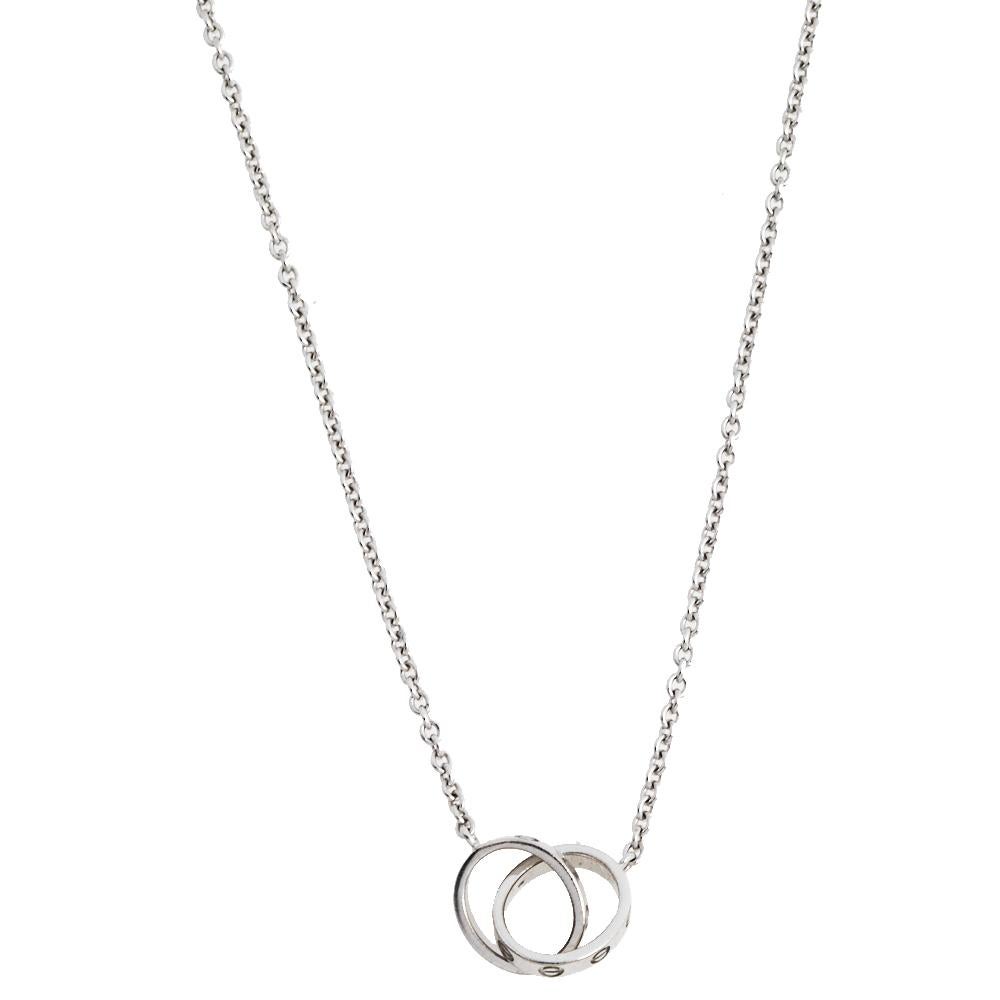 Celebrate timeless love with this necklace from Cartier's Love collection. Made from 18k white gold, it has a chain that holds two magnificent rings interlocked with one another. On both, one can see the iconic screw motifs which are a signature of