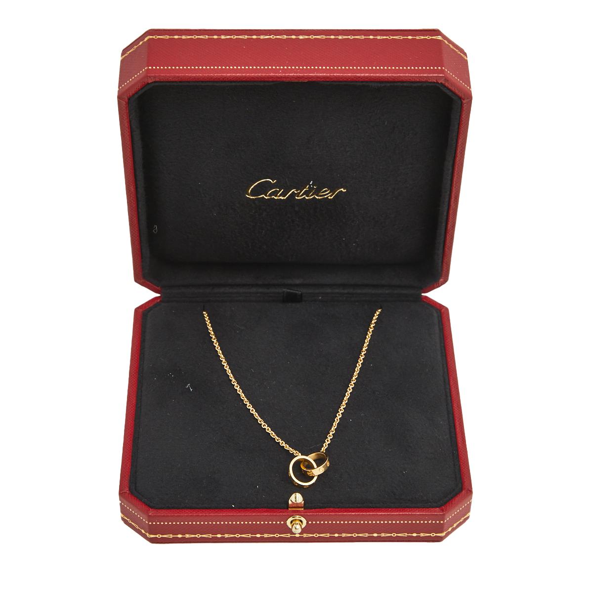 Celebrate timeless love with this necklace from Cartier's Love collection. It is made from 18k yellow gold and the chain holds two magnificent hoops interlocked with one another. Both the rings carry the iconic screw motifs which are a signature of