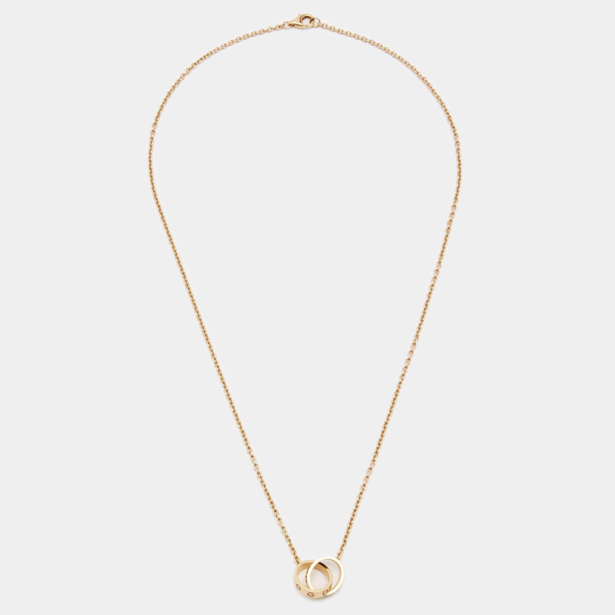 Celebrate timeless love with this necklace from Cartier's Love collection. It is made from 18k rose gold, and the chain holds two magnificent hoops interlocked with one another. Both the rings carry the iconic screw motifs, which are a signature of