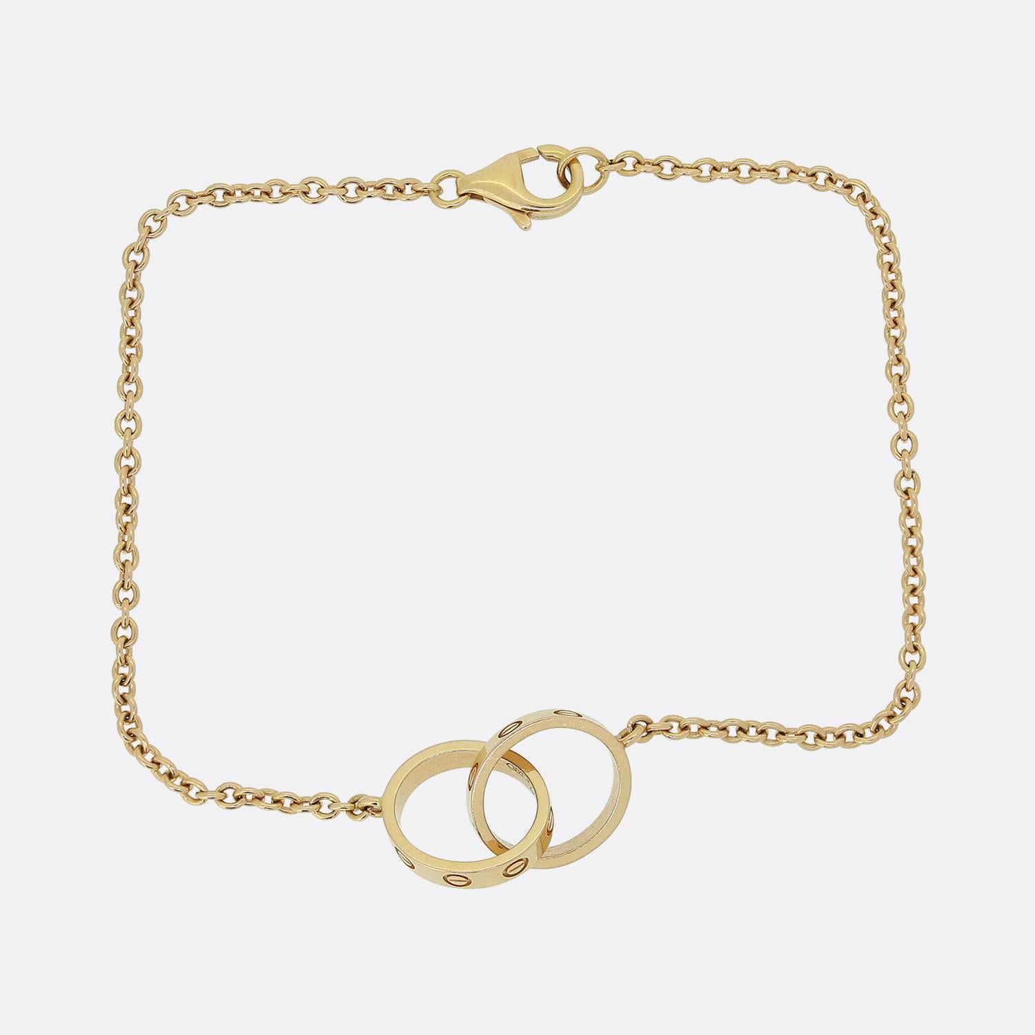 Ecco un braccialetto in oro rosa 18ct della famosa casa di gioielli di lusso Cartier. Questo pezzo in particolare fa parte della collezione LOVE e presenta una coppia di anelli interconnessi con l'iconico motivo a vite, attaccati a una sottile