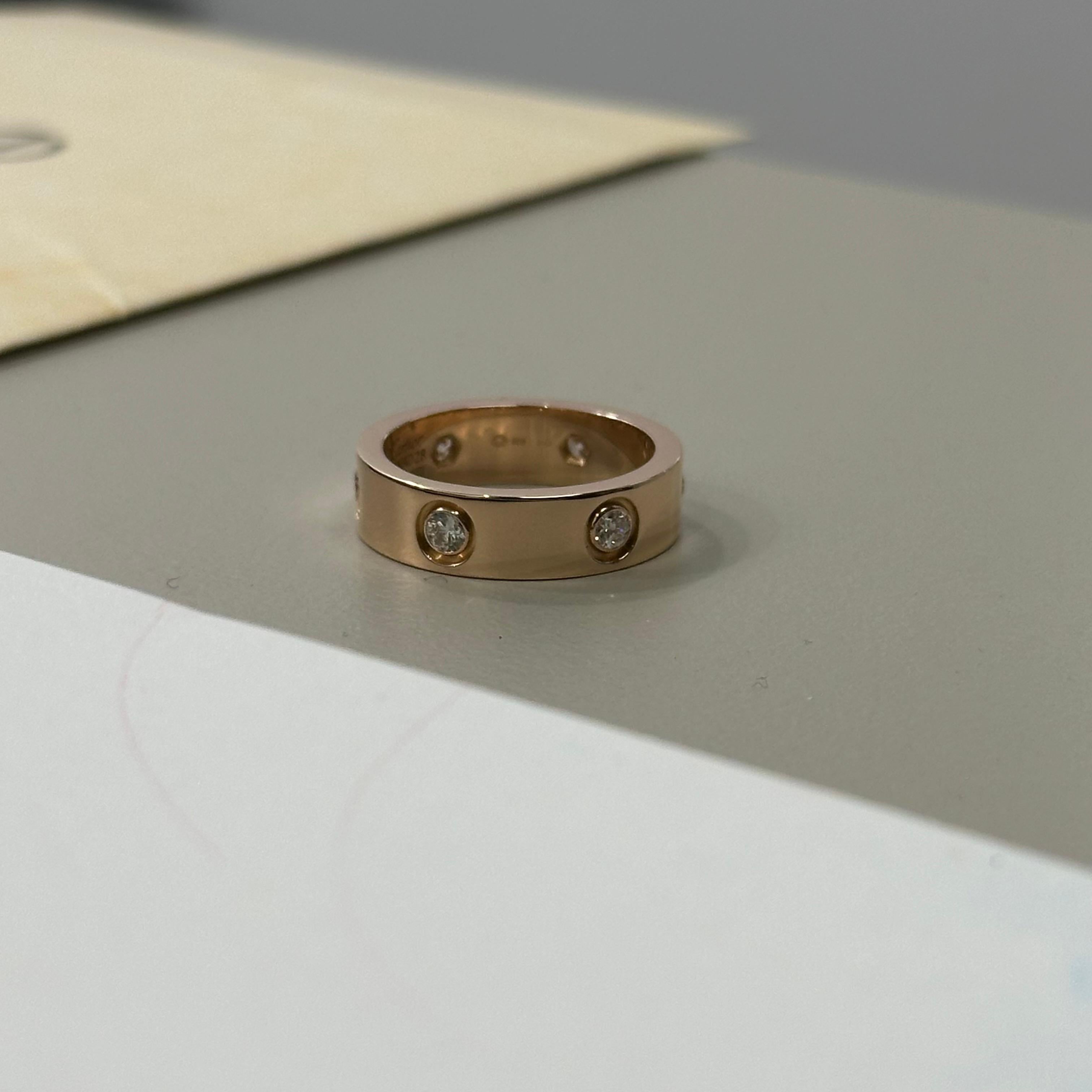 Genuine Cartier Love Ring in rose gold, featuring 6 brilliant cut white diamonds. The ring is hallmarked and signed by Cartier, with a size of 53. It comes with box and papers, and includes seller warranty. This elegant piece is from the Cartier