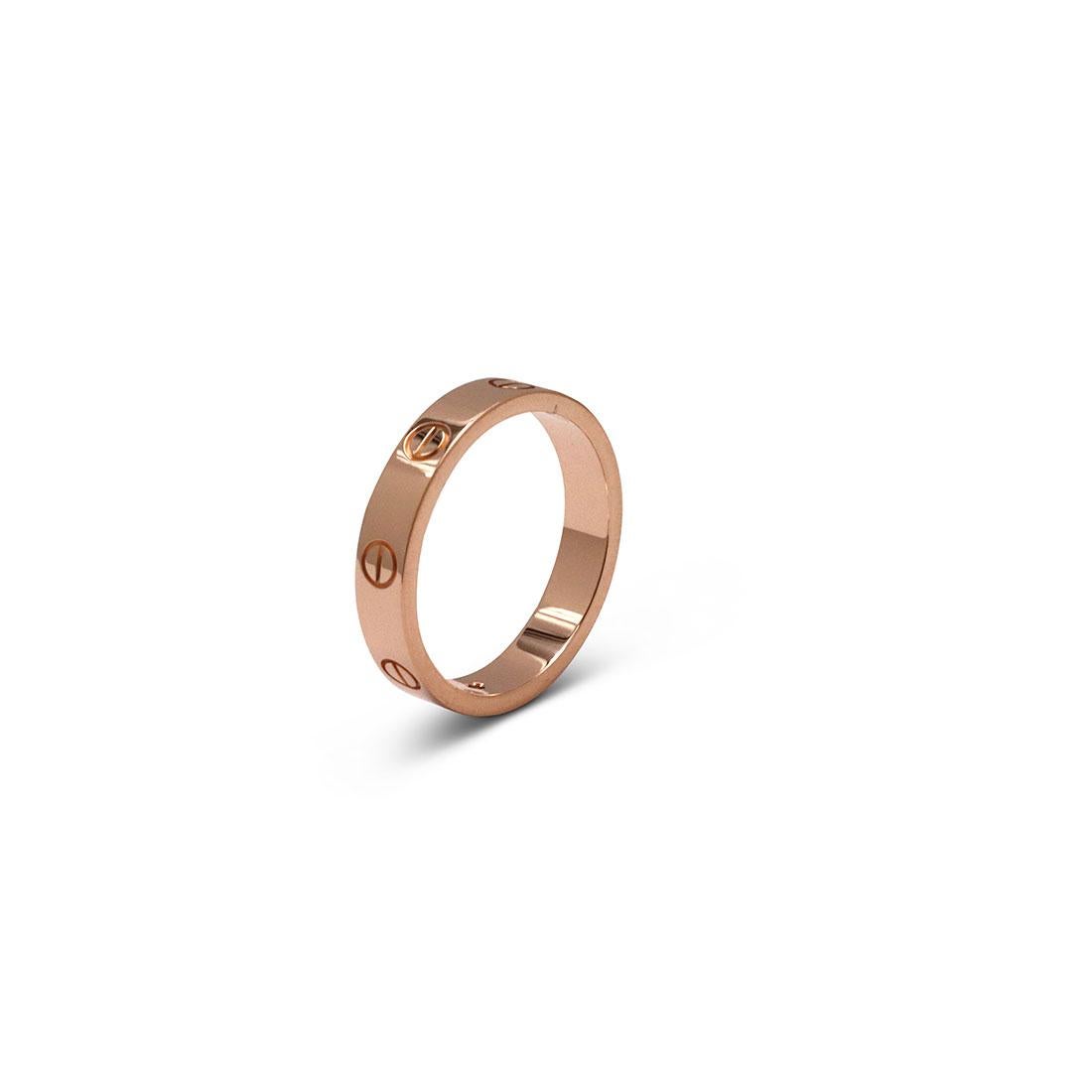 Authentic Cartier 'Love' wedding band crafted in 18 karat rose gold features one round brilliant cut diamond with an estimated 0.02 carat total weight. Signed Cartier, Au750, 56, with serial number and hallmarks. Size 56, (US 7 1/2). The ring is