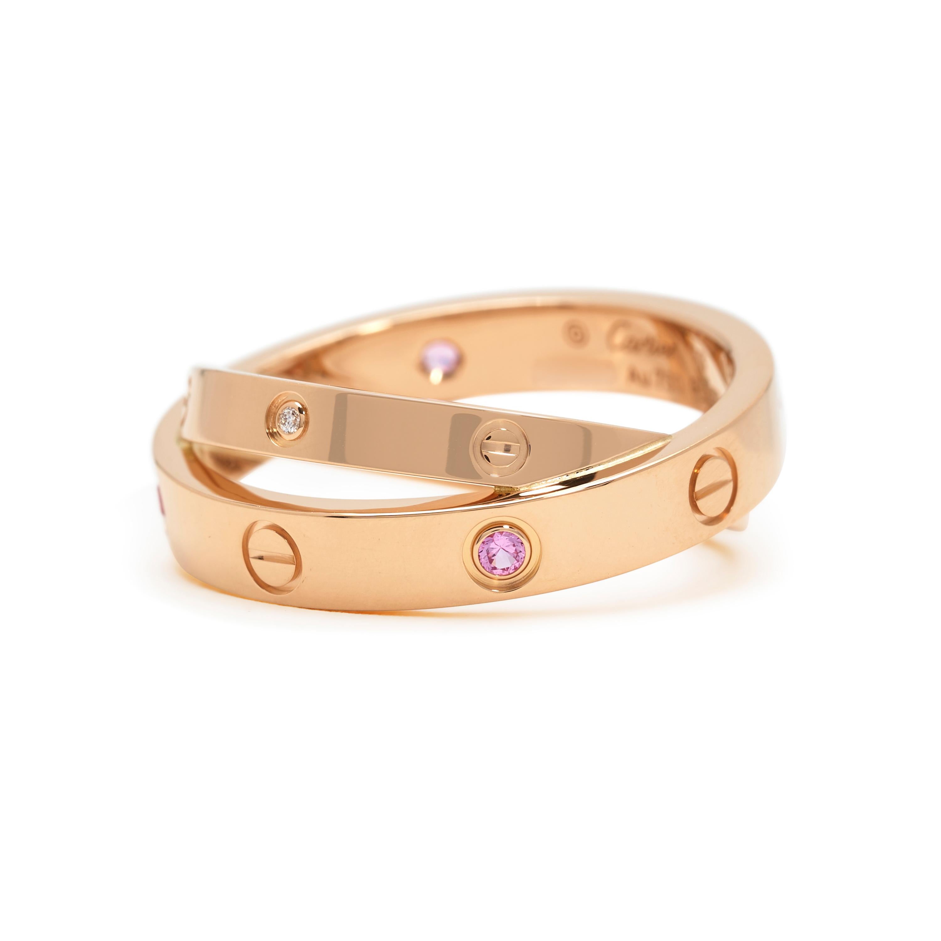 Authentic Cartier Love ring comprised of two bands crafted in 18 karat rose gold.  The wider band is set with four pink sapphires and crosses over a thinner band set with 2 diamonds of an estimated .04 total carats.  Size 53, US 6 1/4.  Signed