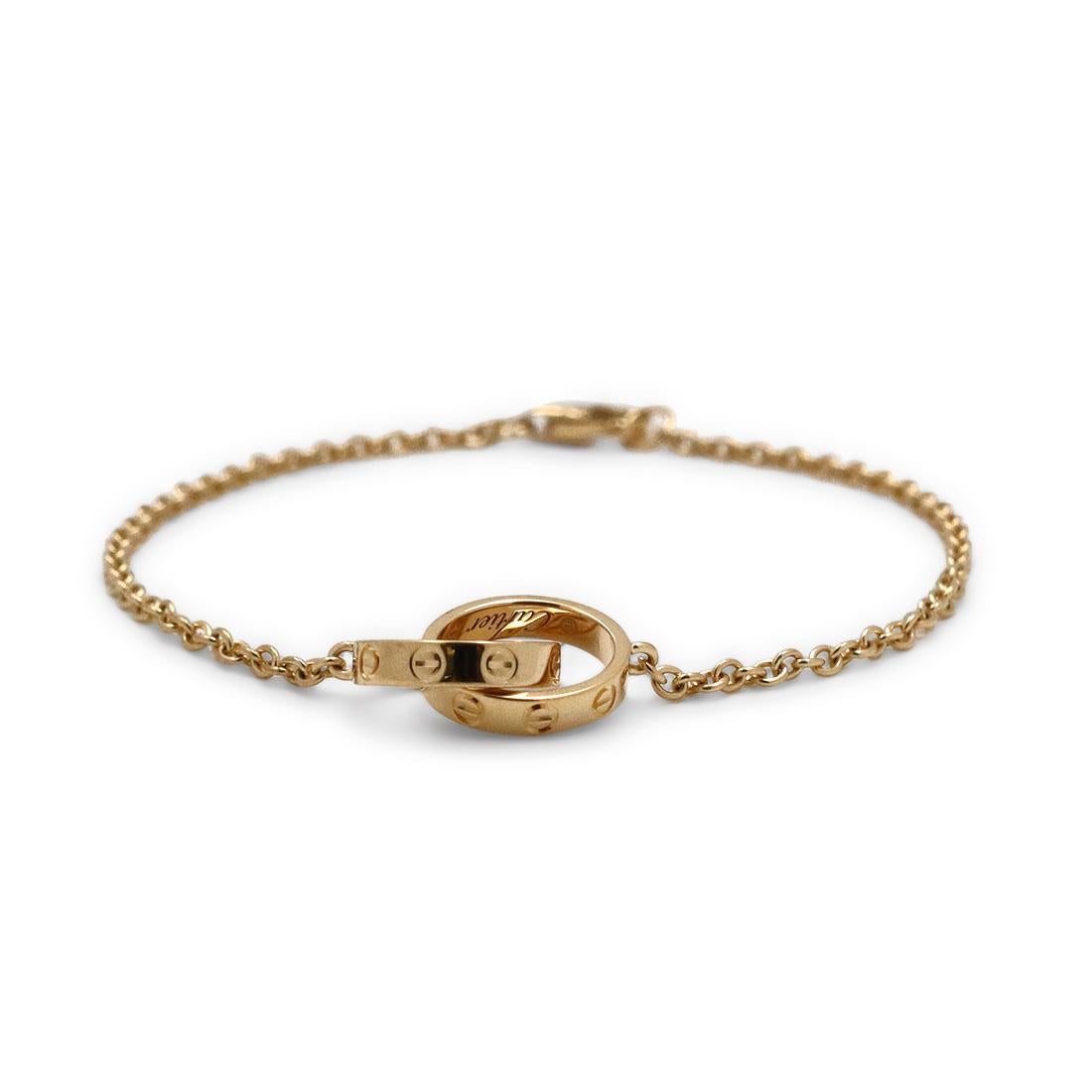 Authentic Cartier 'Love' bracelet crafted in 18 karat yellow gold features two interlocking ove rings in miniature form.  Fits up to a 6-inch wrist. Signed Cartier, Au750, with serial number and hallmarks. Bracelet is not presented with the original