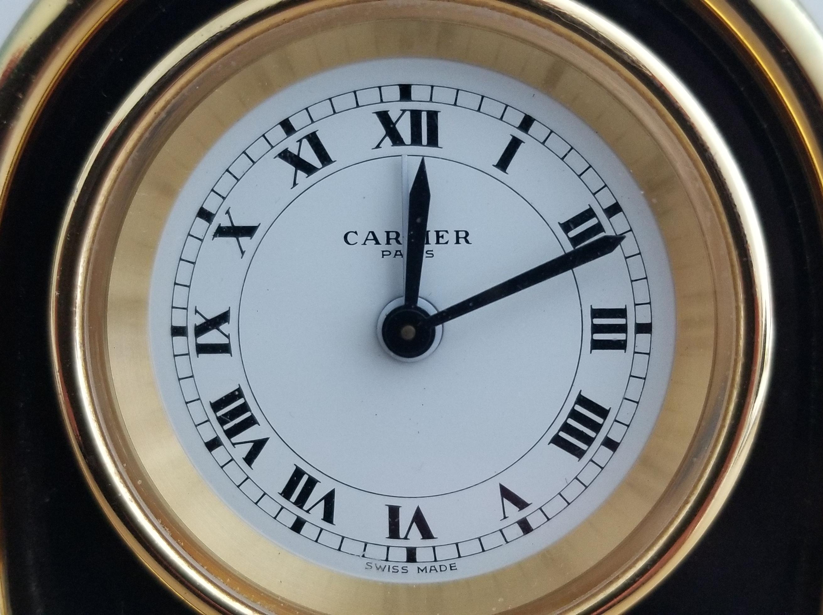 Rare pendulette de voyage mécanique pliante en plaqué or et émail noir de Cartier Paris avec fonction d'alarme. Ce pendulette de bureau ou de table de style Art déco présente les caractéristiques suivantes : mouvement mécanique à remontage manuel ;