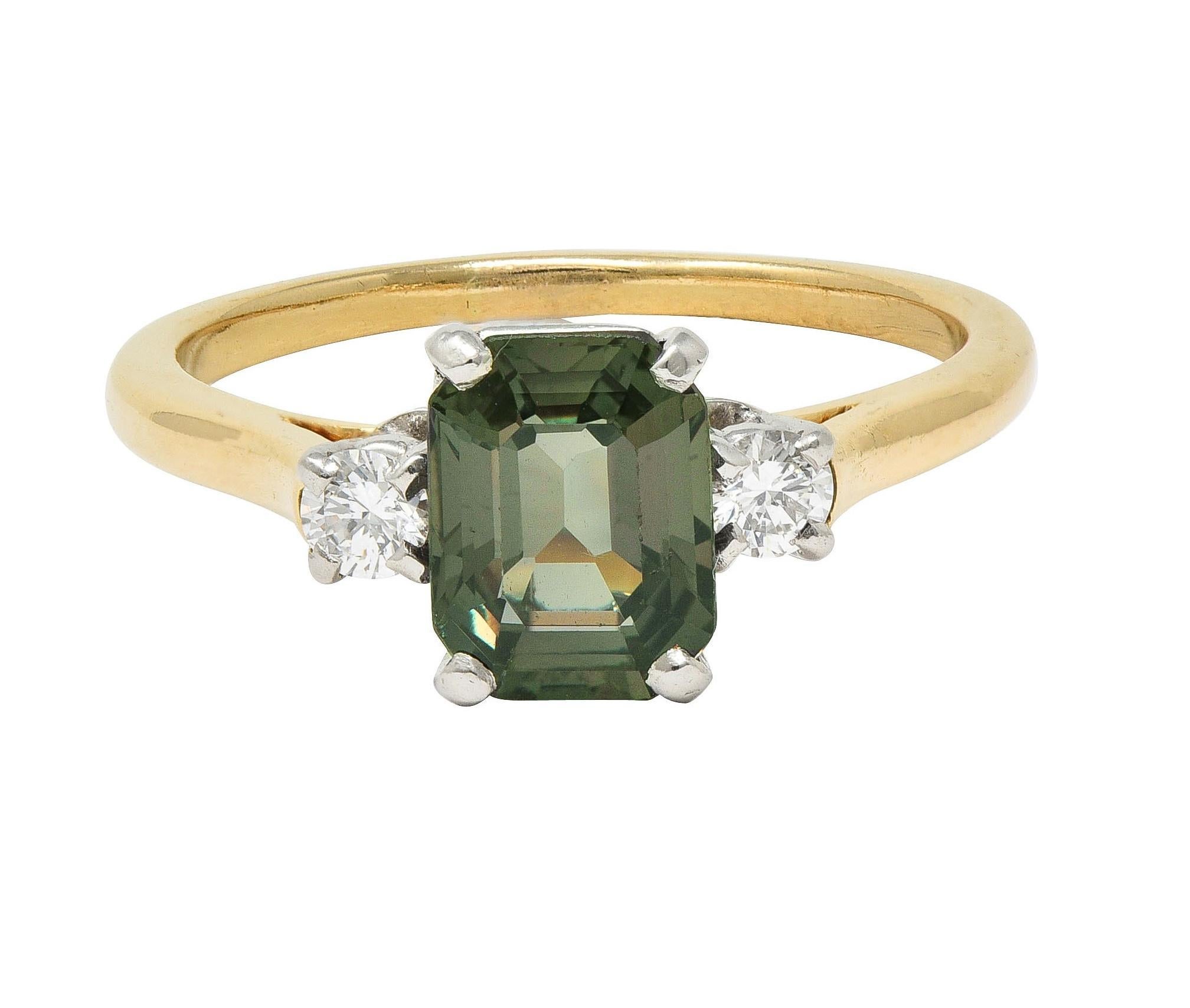 Centering an emerald cut alexandrite weighing approximately 1.50 carats total - transparent dark green
Displaying moderate color change to dark brownish red in incandescent light 
Flanked by round brilliant cut diamonds - each prong set in platinum