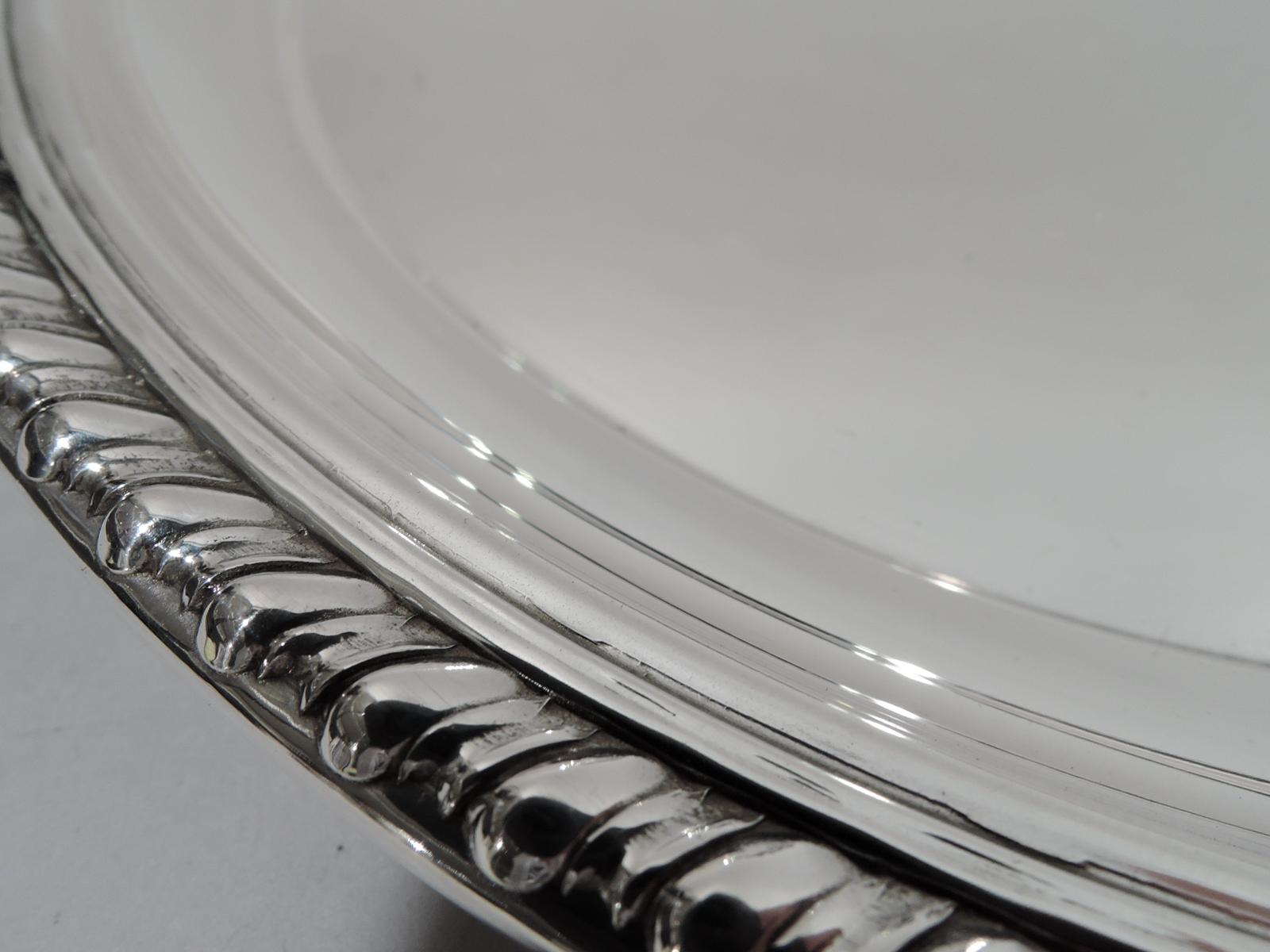 Midcentury classical sterling silver tray. Retailed by Cartier in New York. Round well, curved sides, and gadrooned rim. Fully marked including retailer’s stamp. Weight: 8.5 troy ounces.