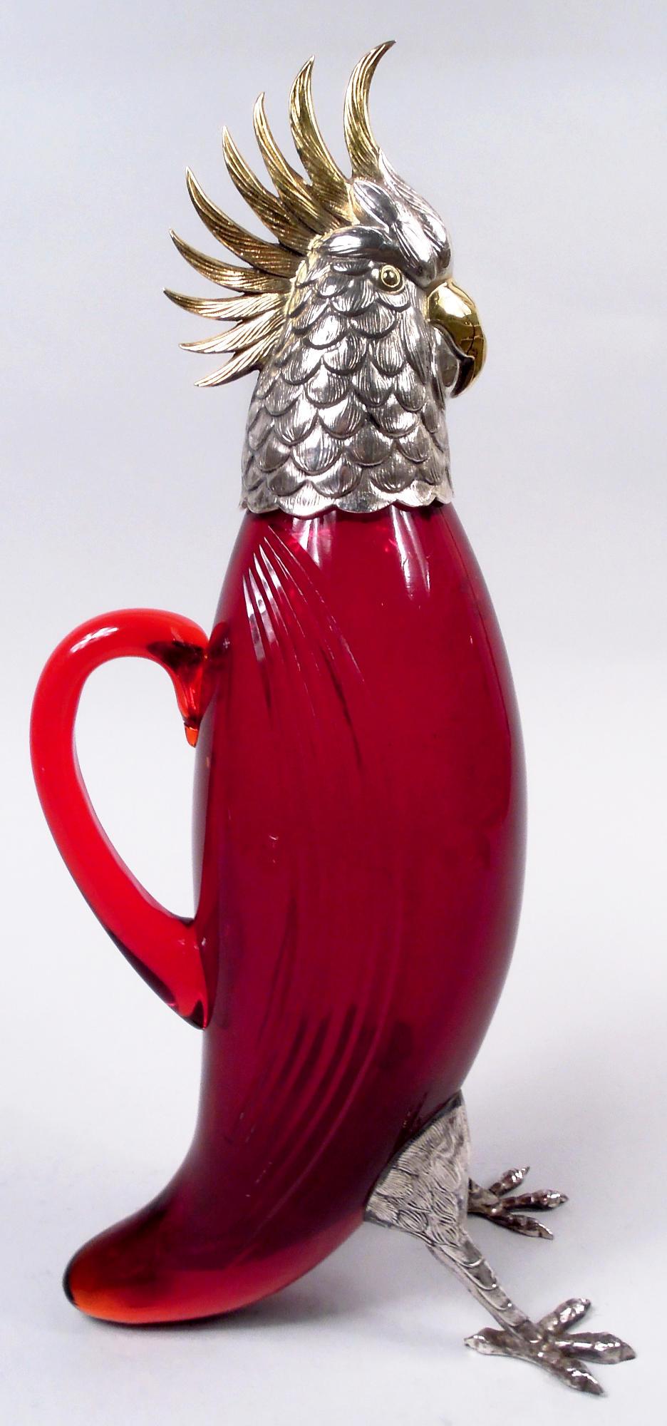 Carafe figurative en argent sterling et verre rouge du milieu du siècle dernier. Revendu par Cartier à New York. Un drôle de cacatoès flamboyant. Corps en verre ovoïde avec des ailes représentées par des cannelures incurvées taillées ; queue effilée