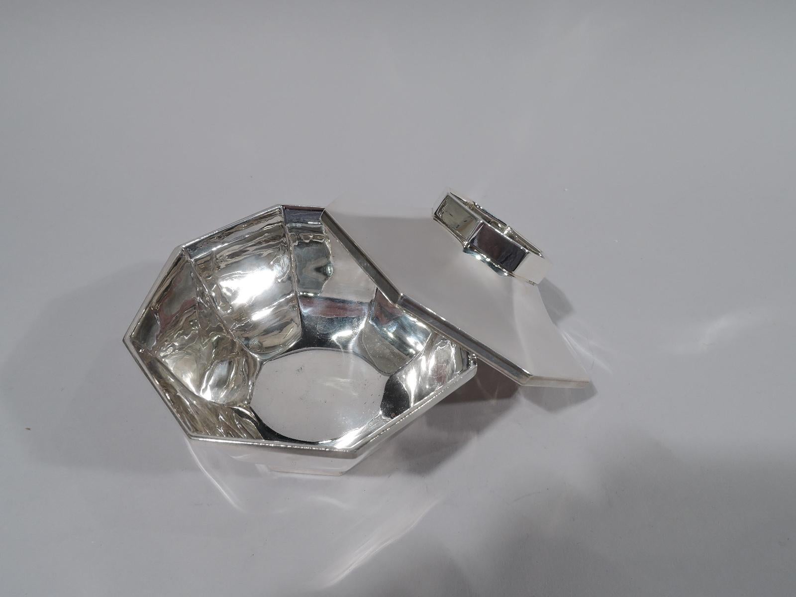 Mid-Century Modern sterling silver bowl. Retailed by Cartier in New York. Curved and faceted sides with flat rim and inset same foot. Cover faceted and overhanging with inset faceted gallery. Stylish geometric form. Fully marked including maker’s